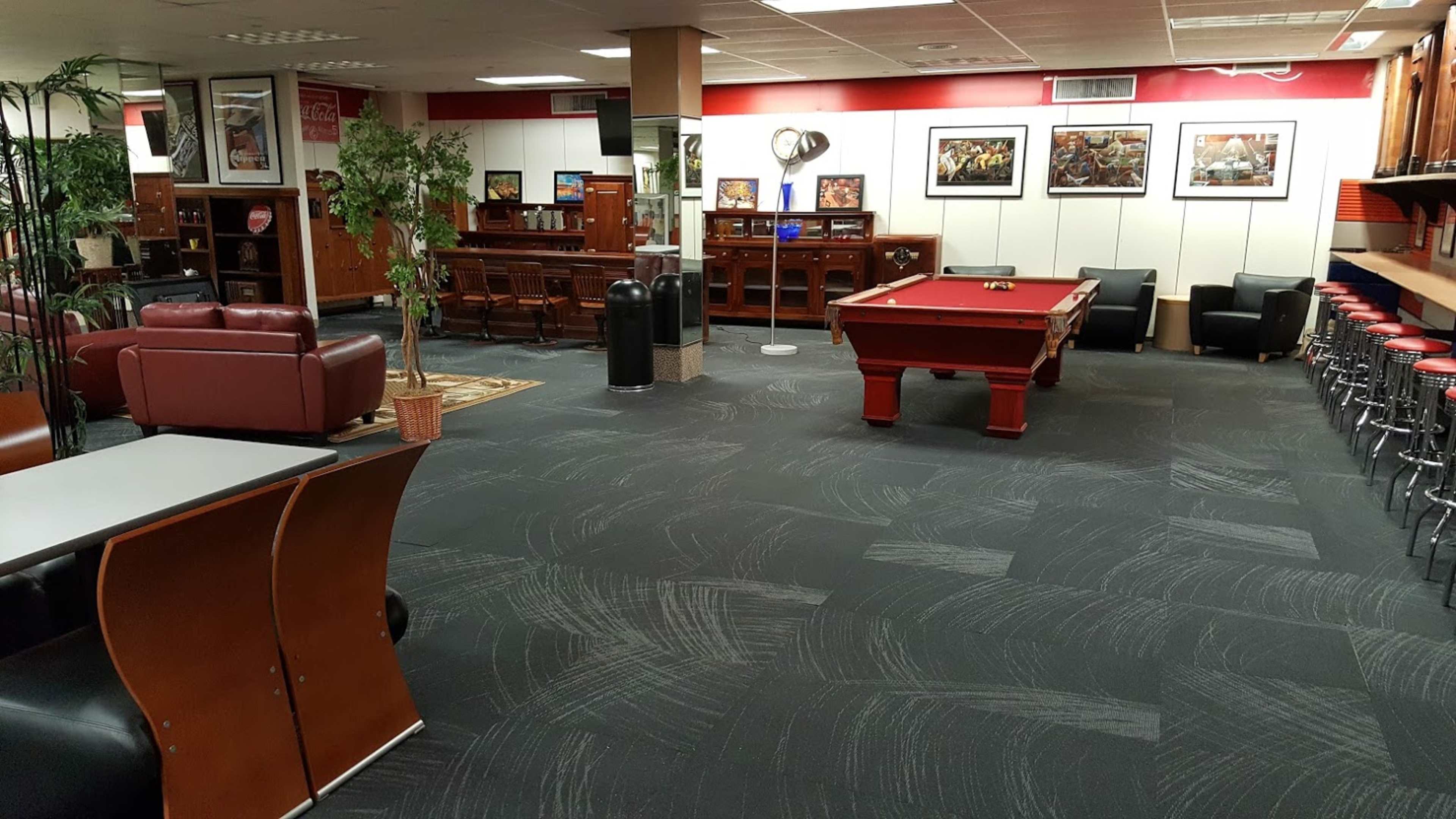 A lounge area featuring a pool table, bar seating, various pieces of furniture, and framed artwork on the walls.
