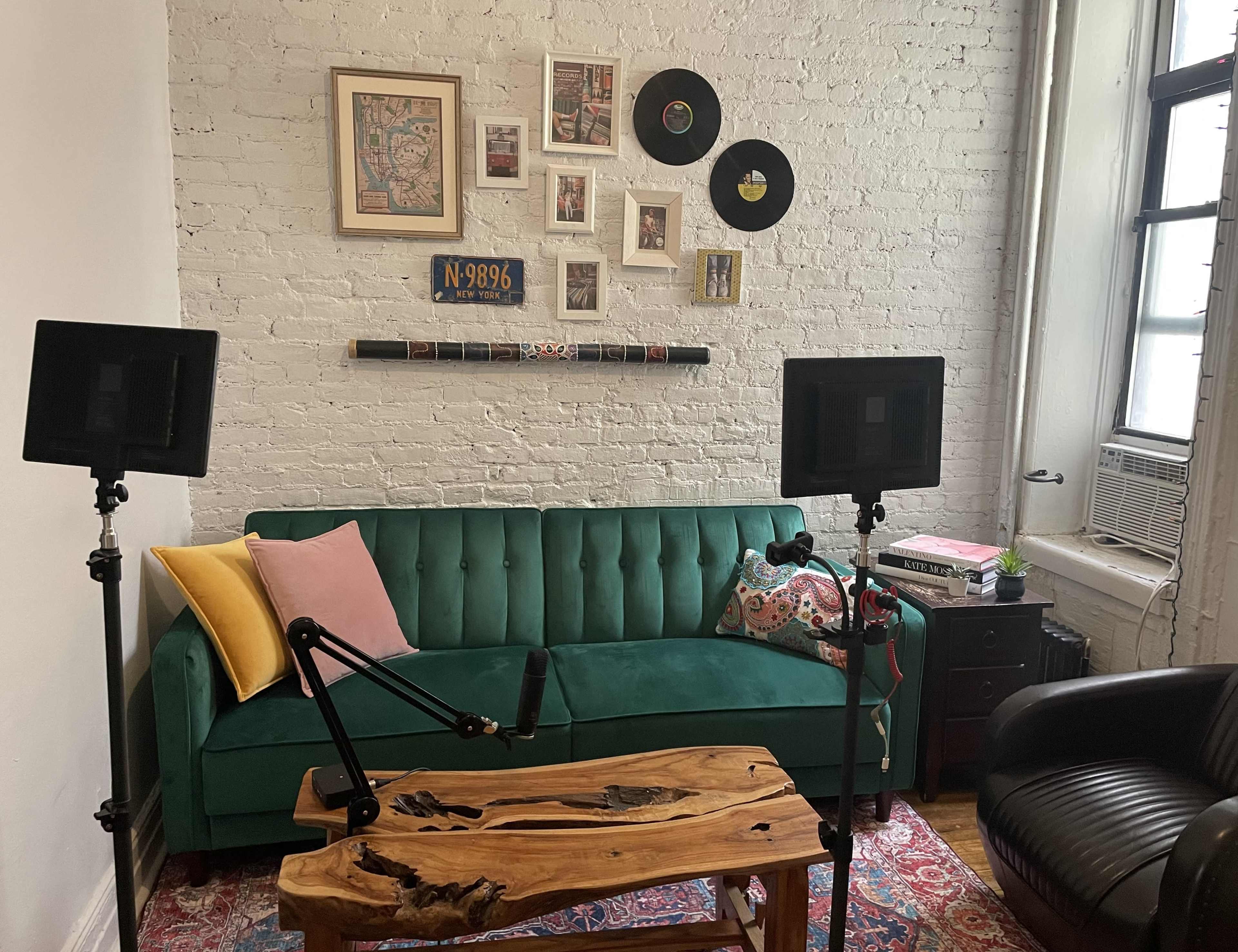 A cozy living room with a green sofa, a wooden coffee table, and wall decorations, including framed artwork and vinyl records.
