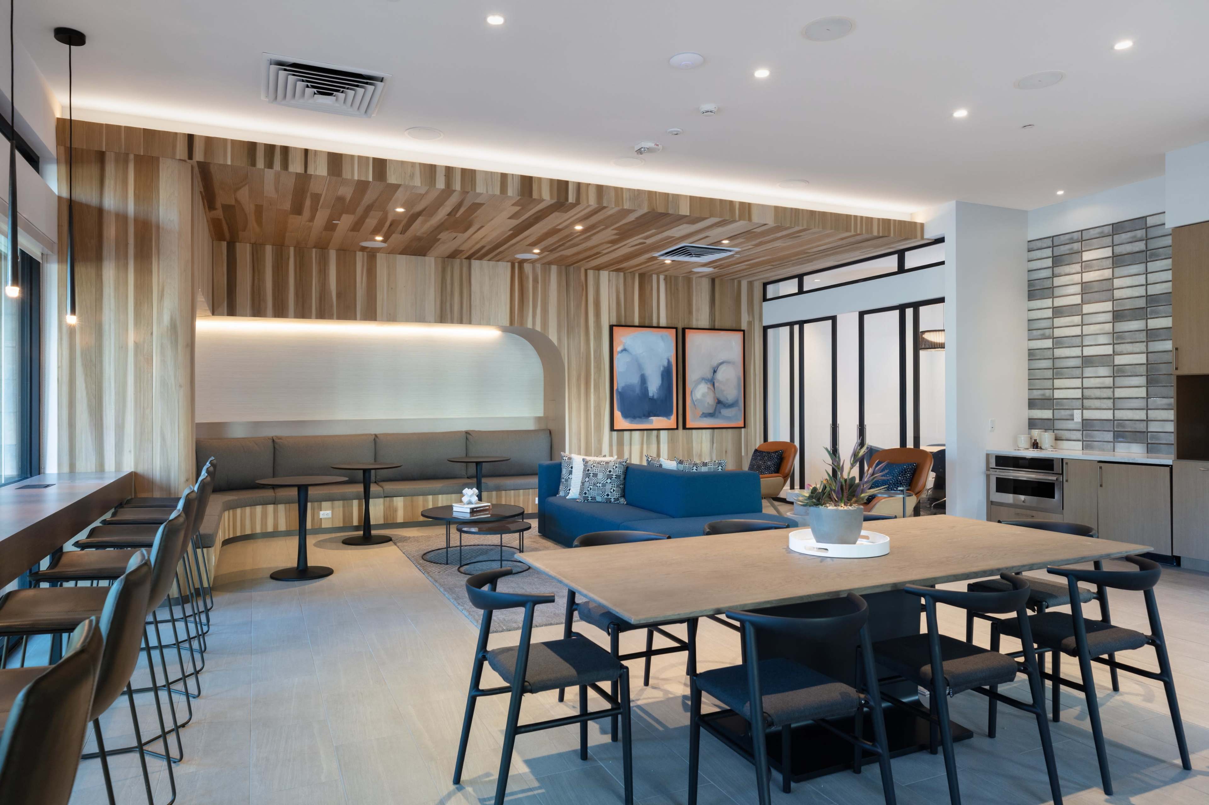 A modern lounge area with wooden wall paneling, a seating arrangement, and artwork on the walls.