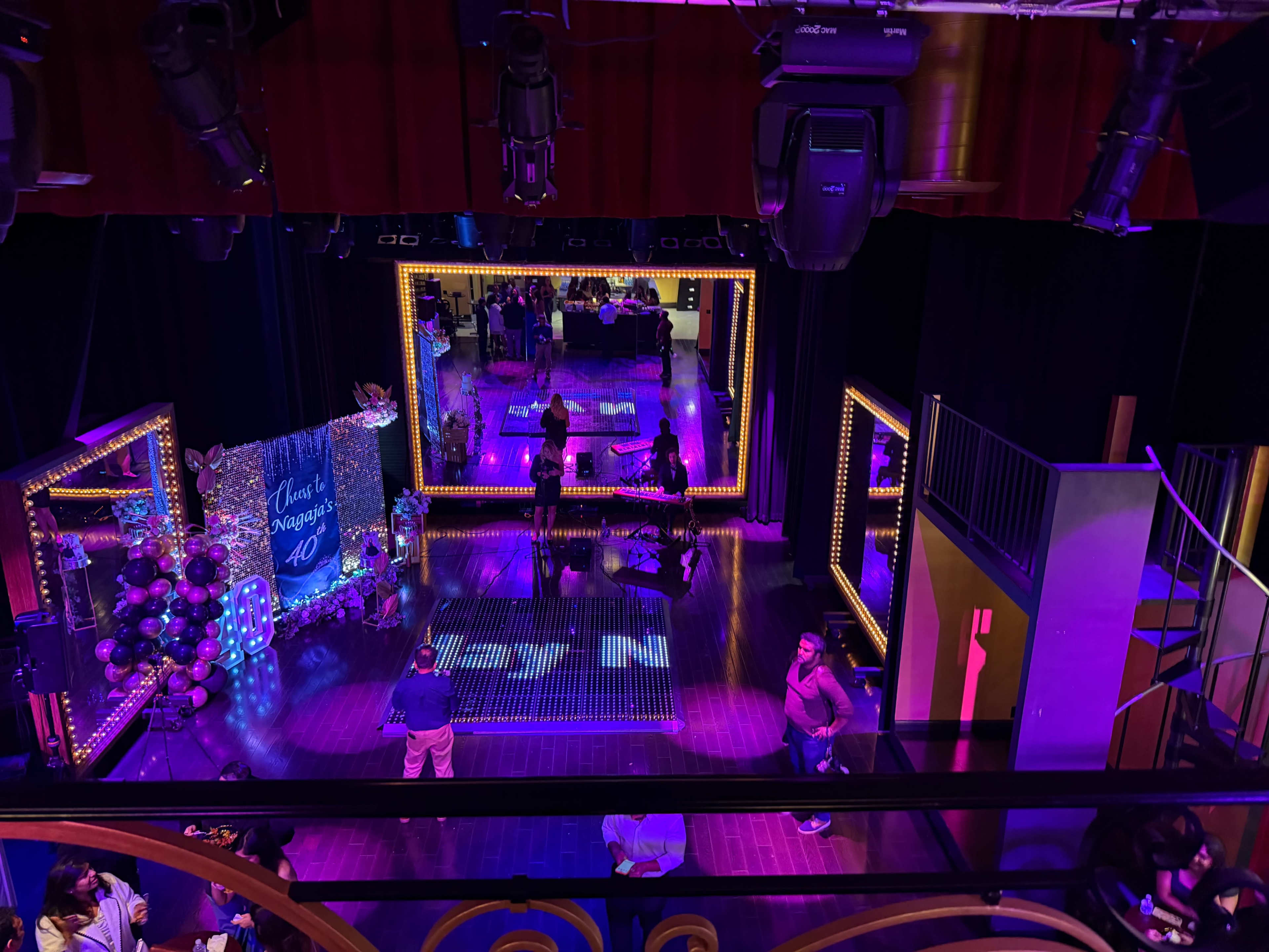 The image depicts a vibrant event space with colorful lighting, featuring mirrors and decorative elements, set up for a celebration.