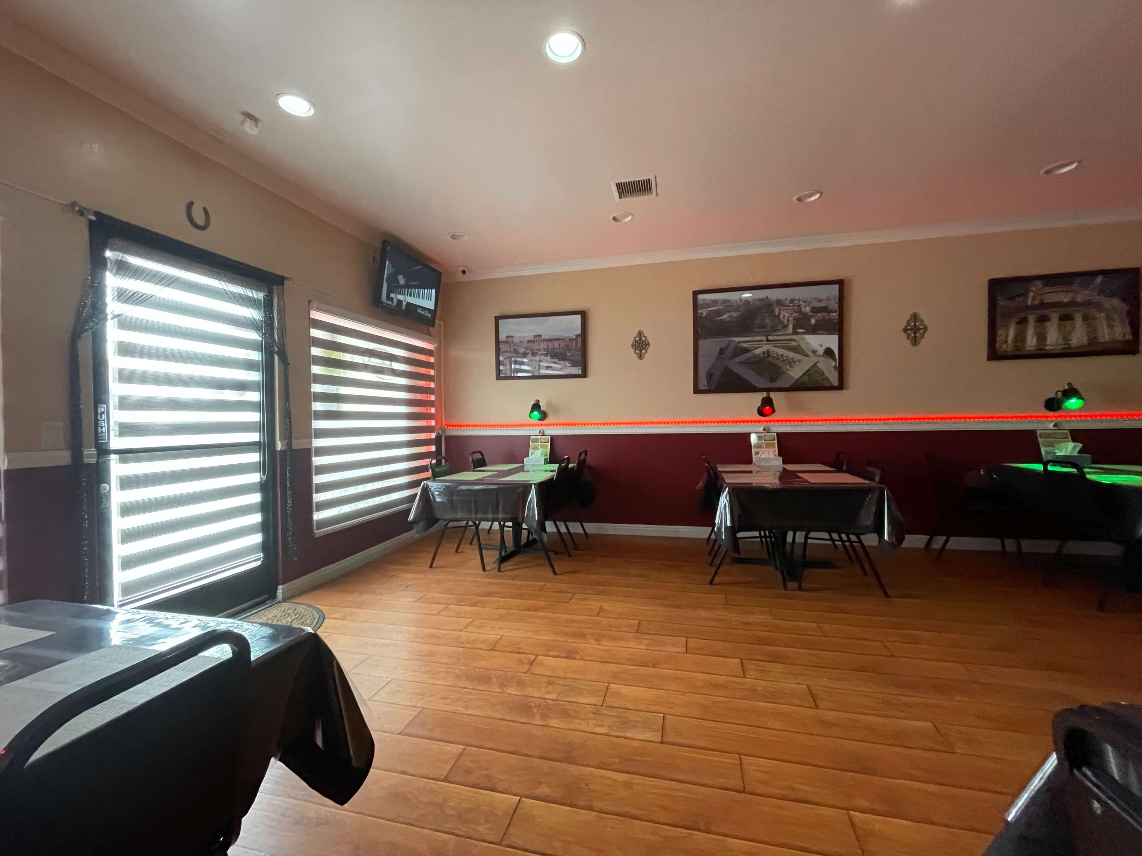 The image shows a restaurant interior with empty tables, artwork on the walls, and red lighting along a central strip.