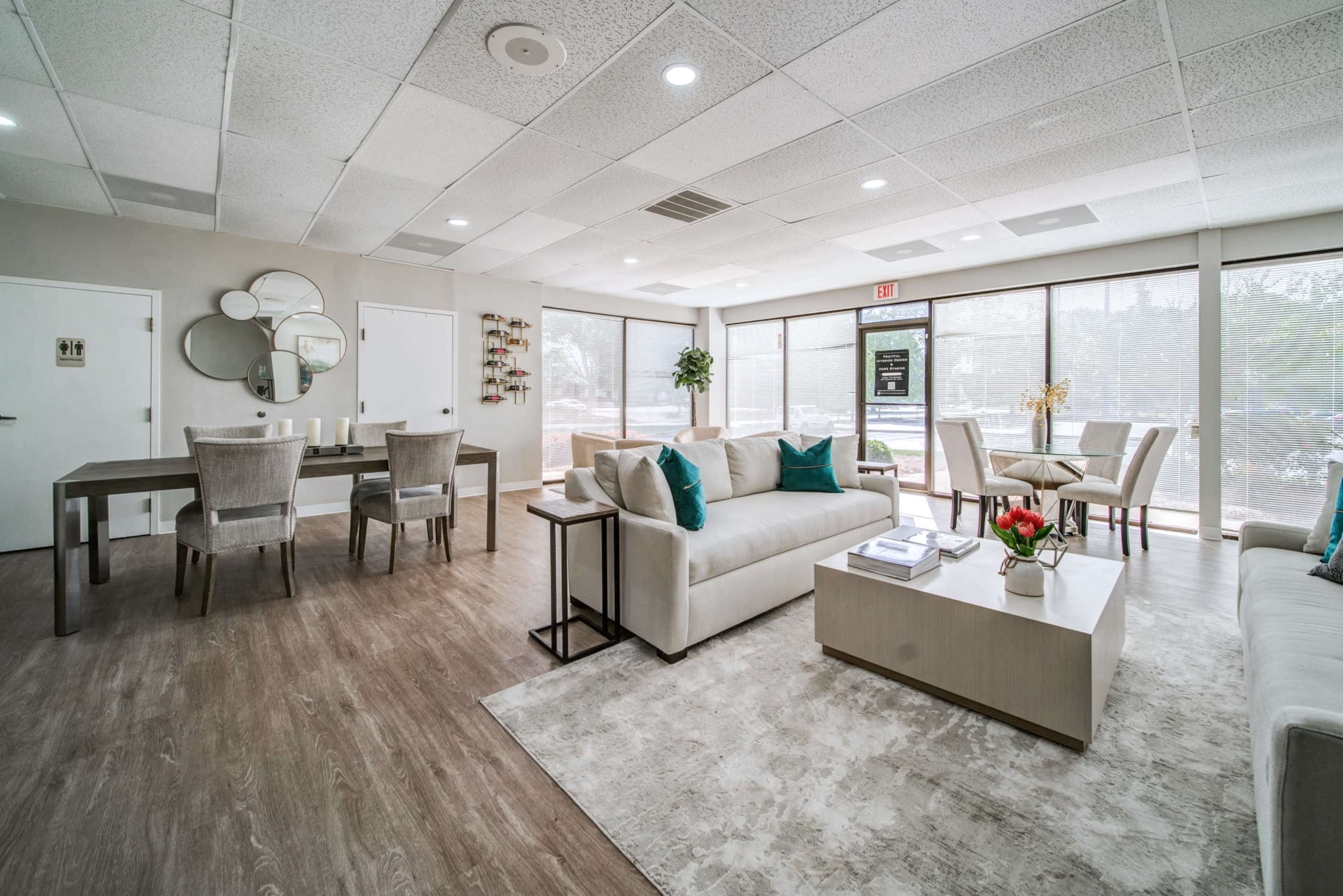 A modern room with a seating area, dining table, and large windows allowing natural light to enter.