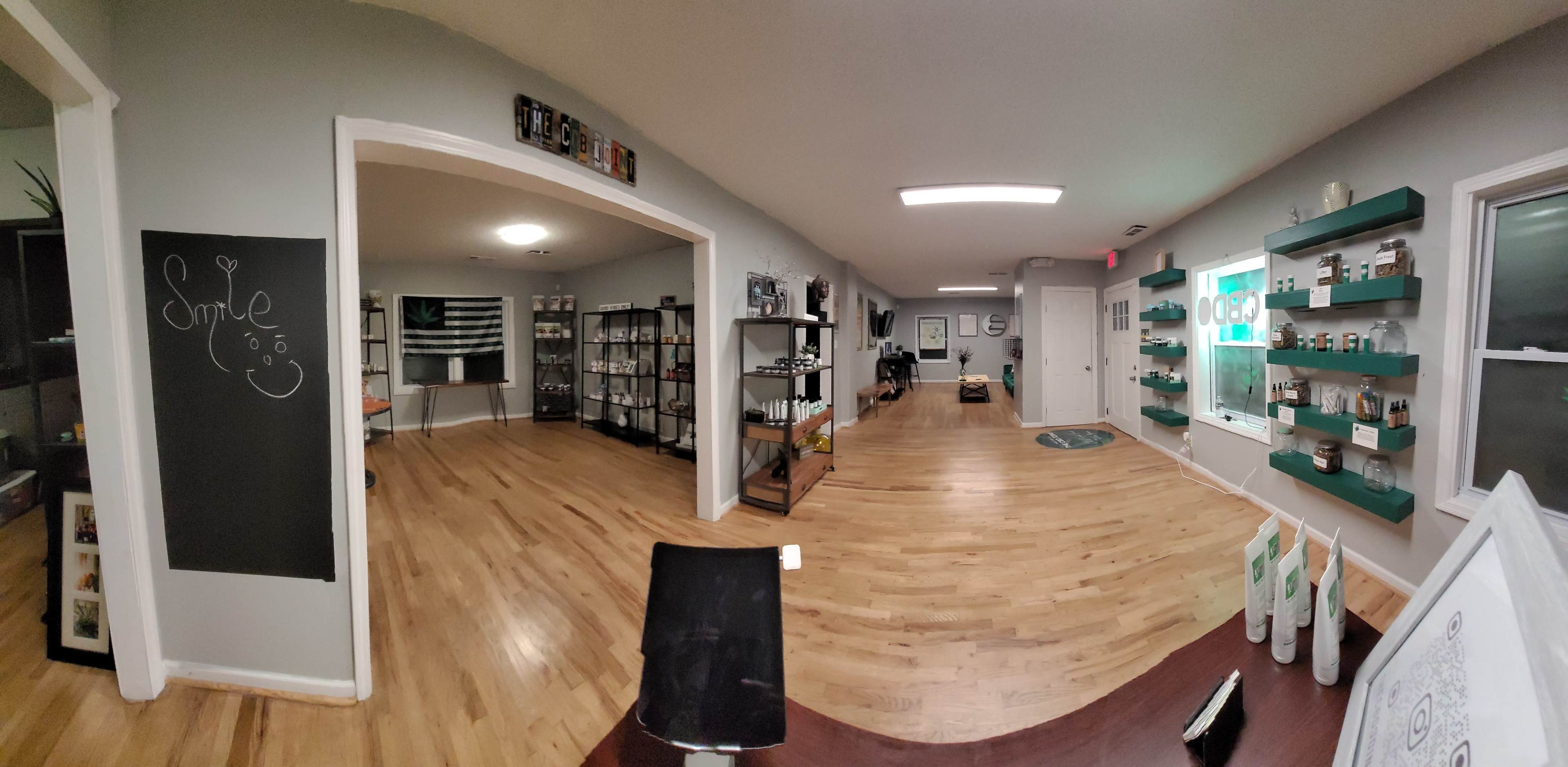 A spacious, well-lit salon or wellness center with wooden flooring, shelves displaying products along the walls, and a welcoming reception area.