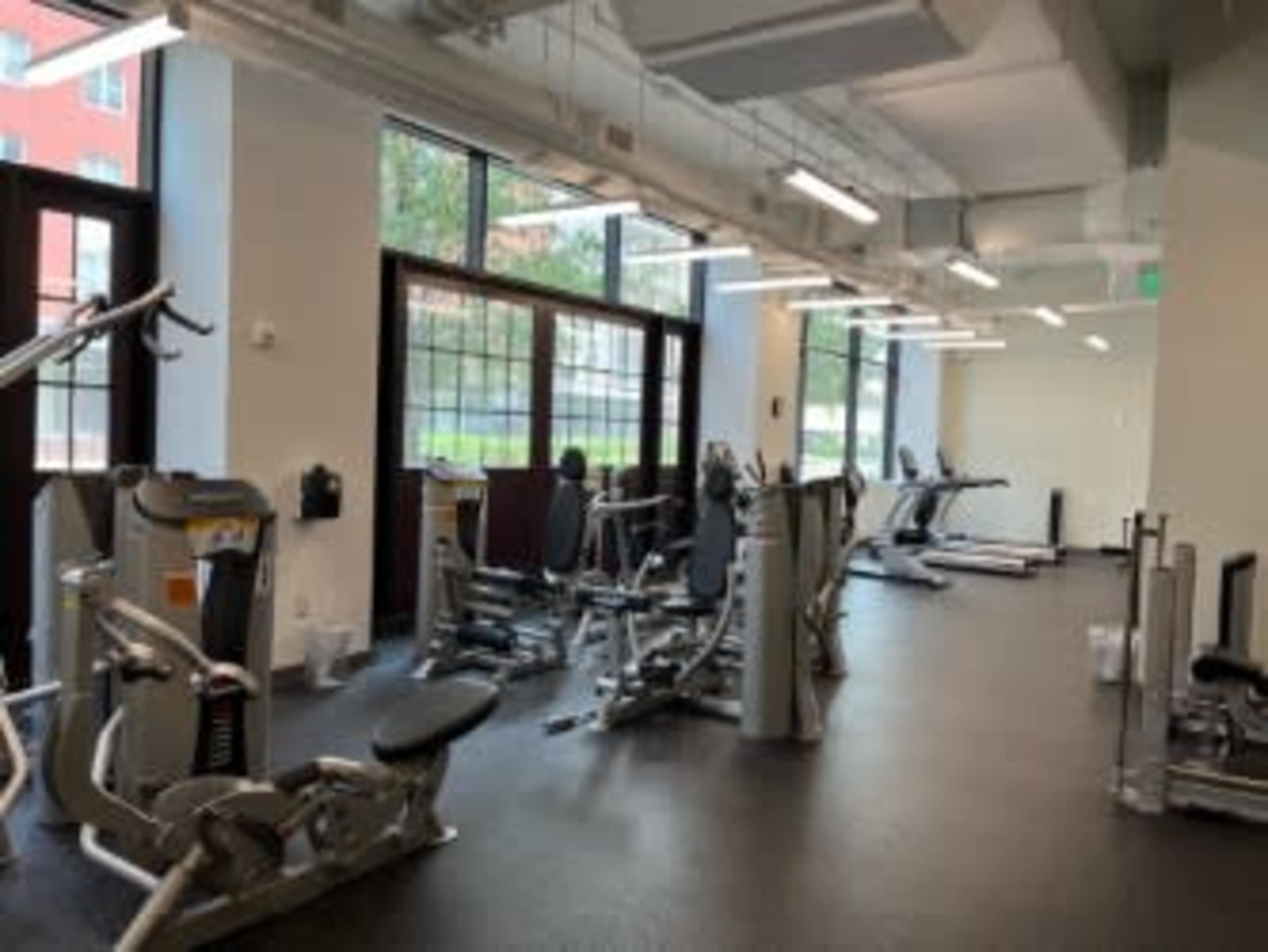 A fitness gym with various exercise machines and equipment arranged in a well-lit space.