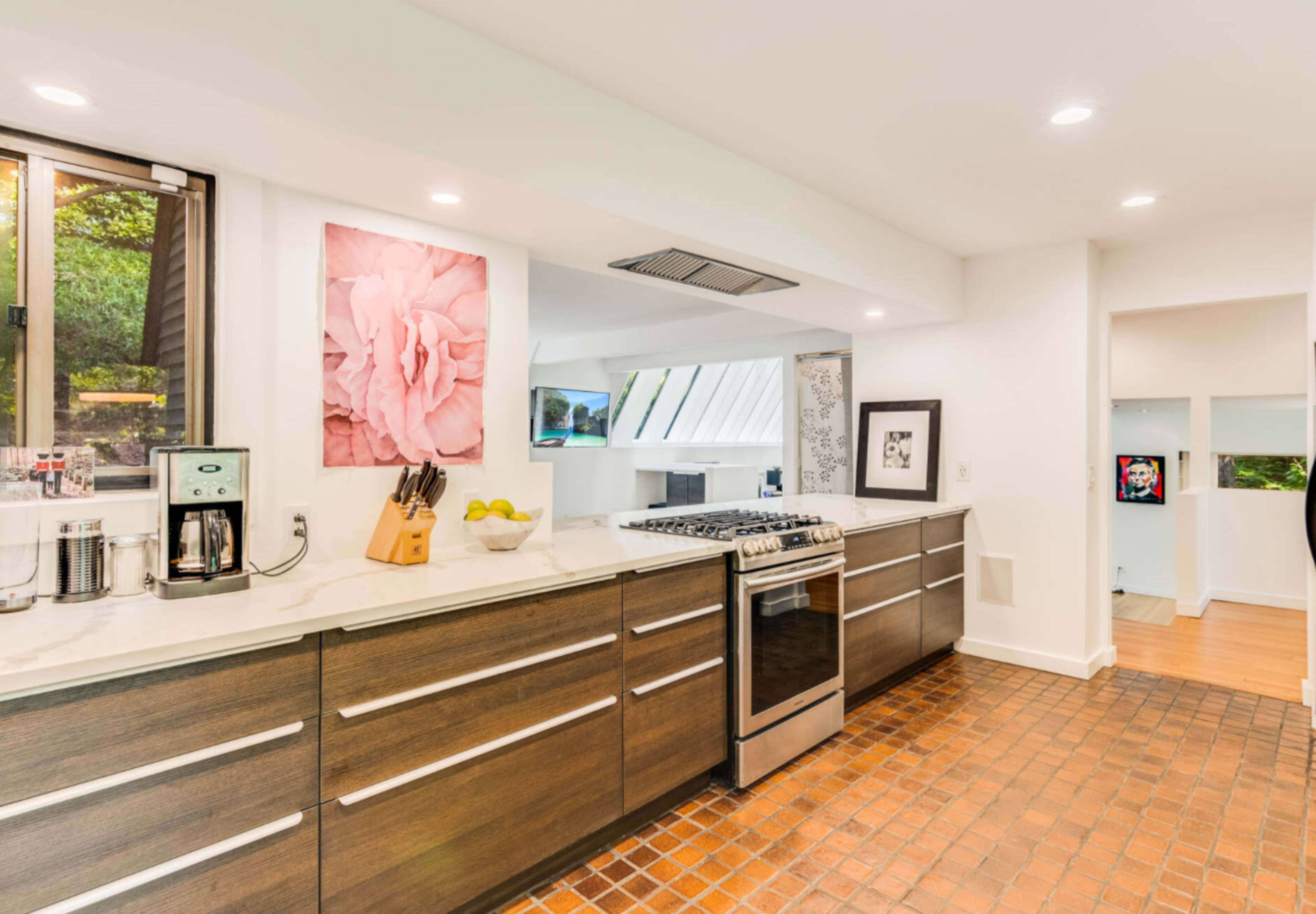 The kitchen features modern cabinetry, a stainless steel stove, and a large window allowing natural light to enter.