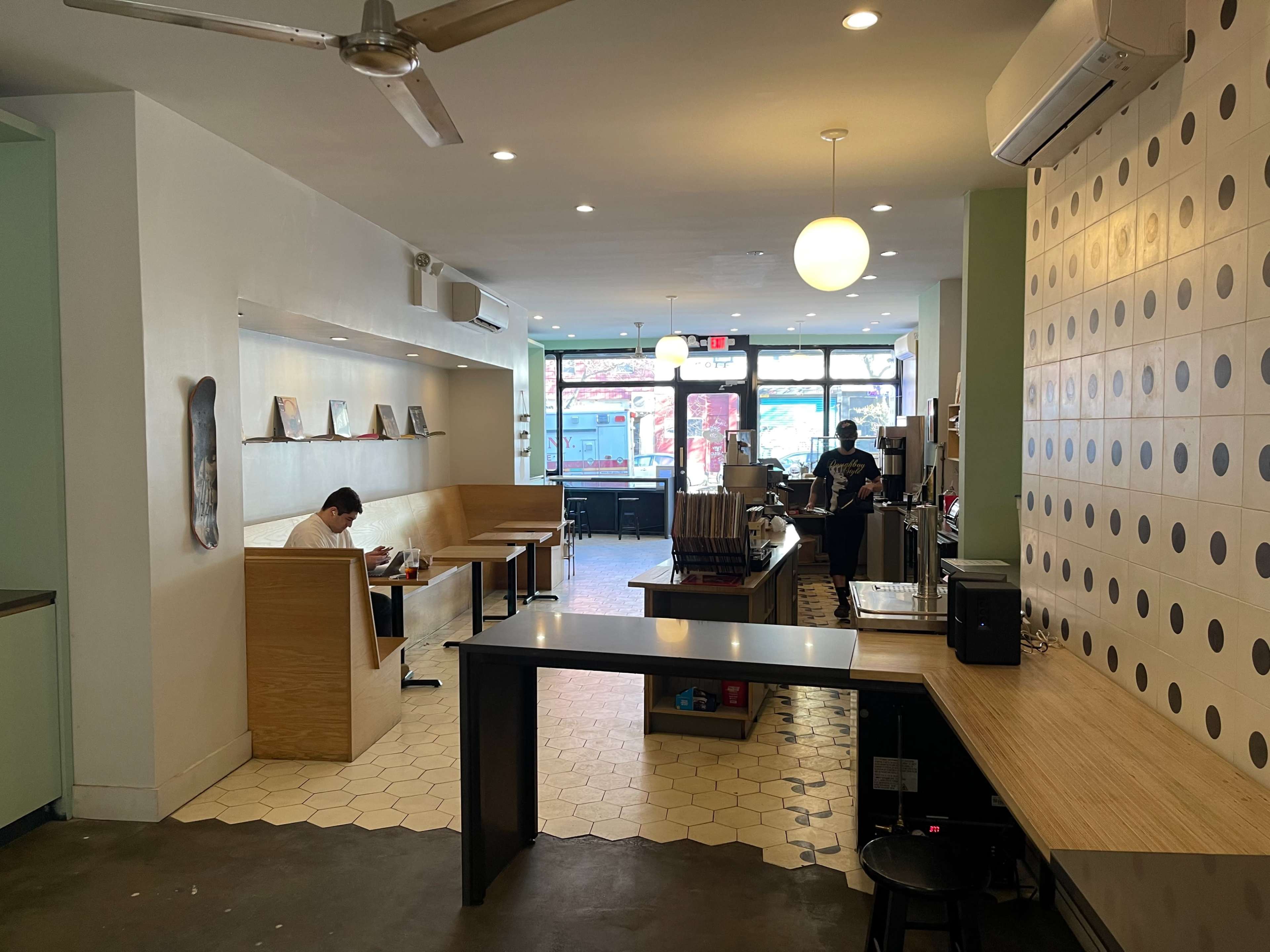A spacious café interior with seating areas, a counter, and large front windows that allow natural light in.