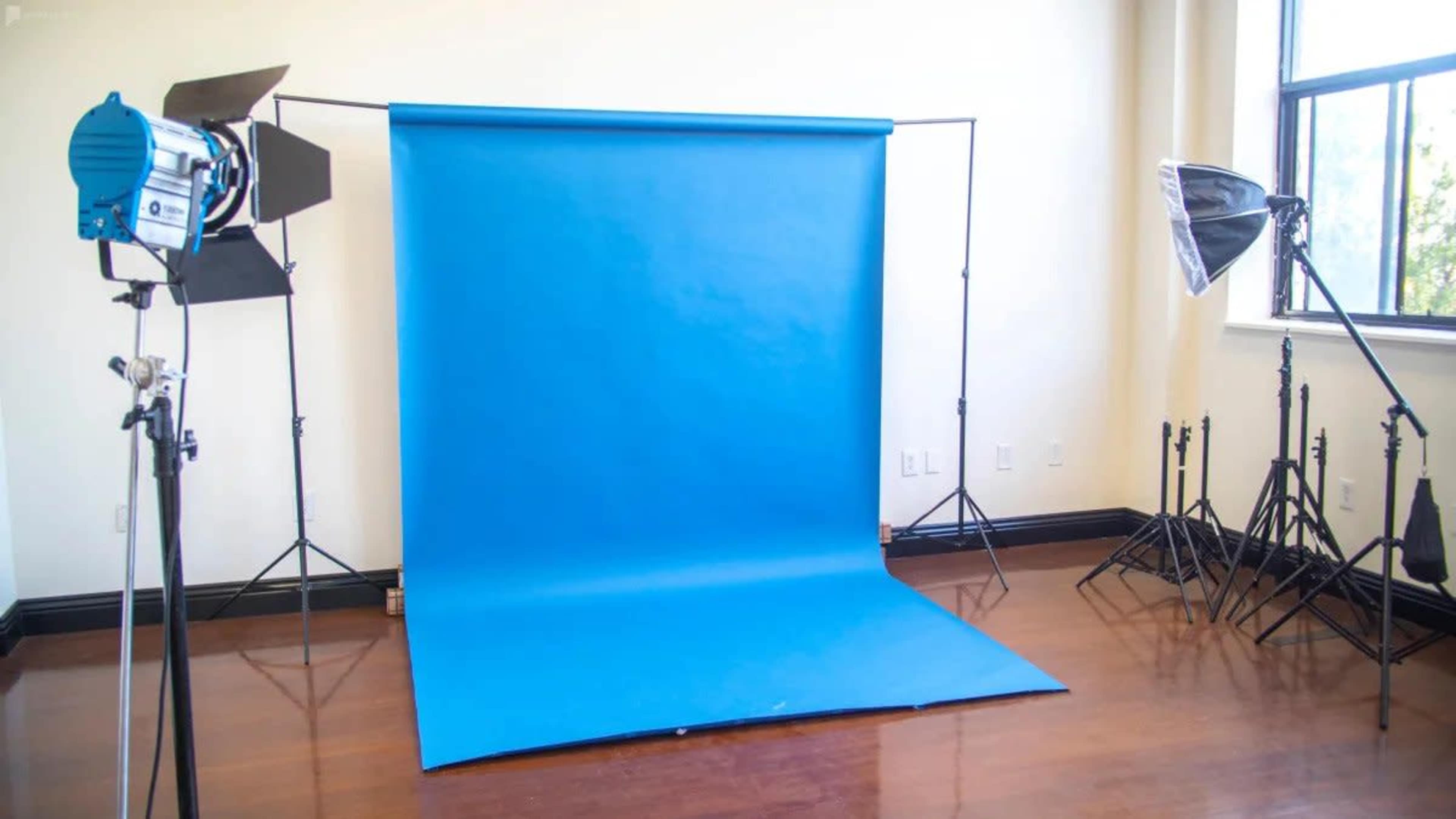 A photography studio setup with a blue backdrop and lighting equipment on either side.