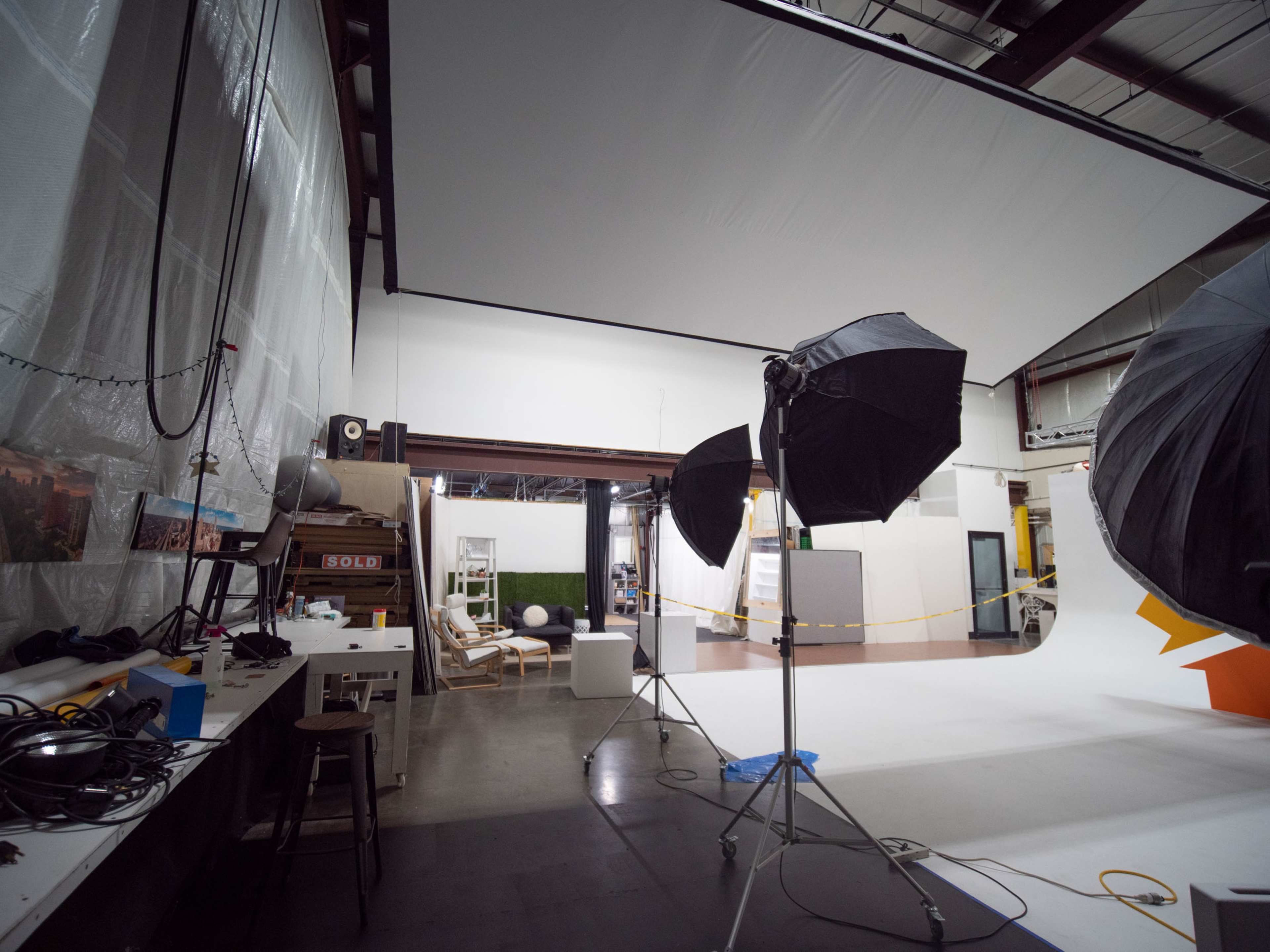 A photography studio with lighting equipment, a backdrop setup, and various props arranged in the space.