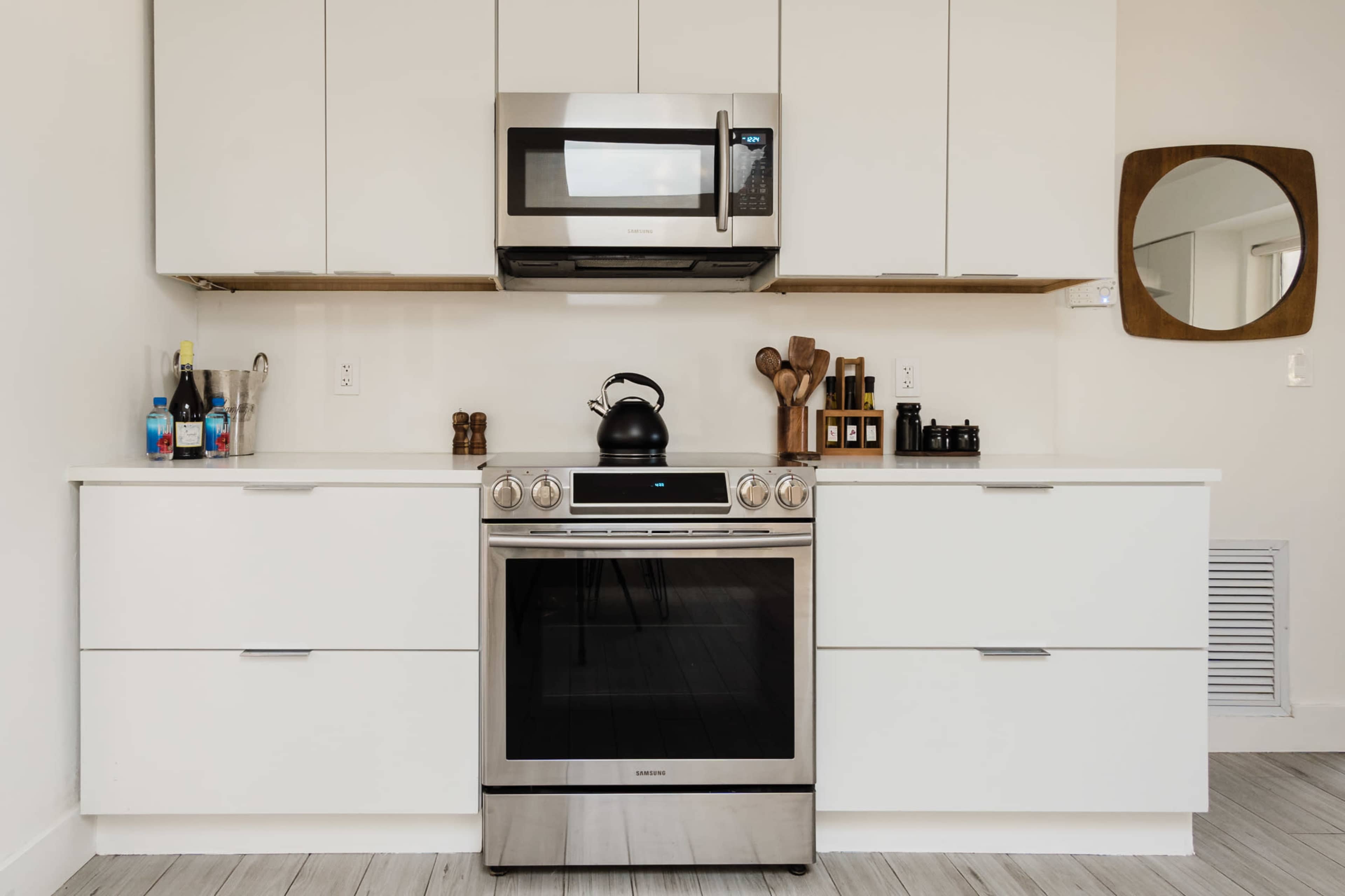 A modern kitchen with stainless steel appliances, including a microwave and stove, and a tidy arrangement of utensils and bottles on the countertop.