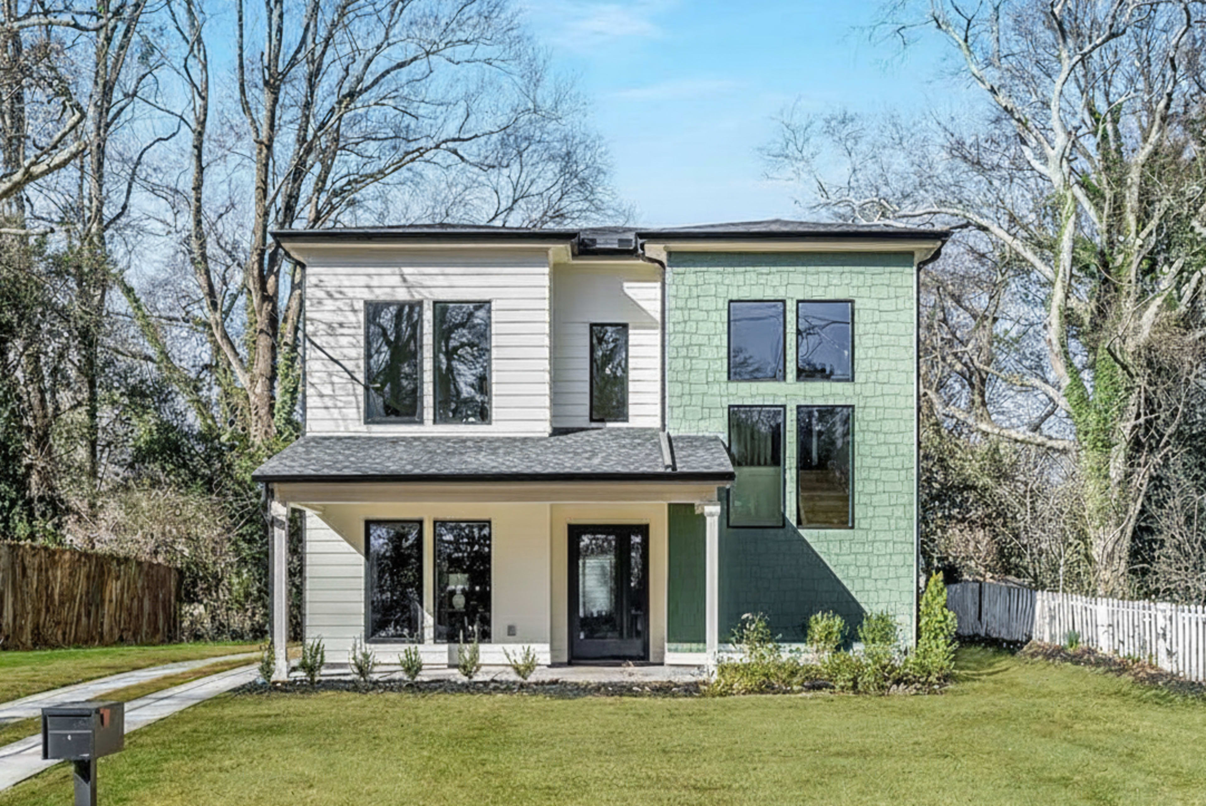 The image shows a modern two-story house with a mix of light-colored siding and green accents, surrounded by a lawn and trees.
