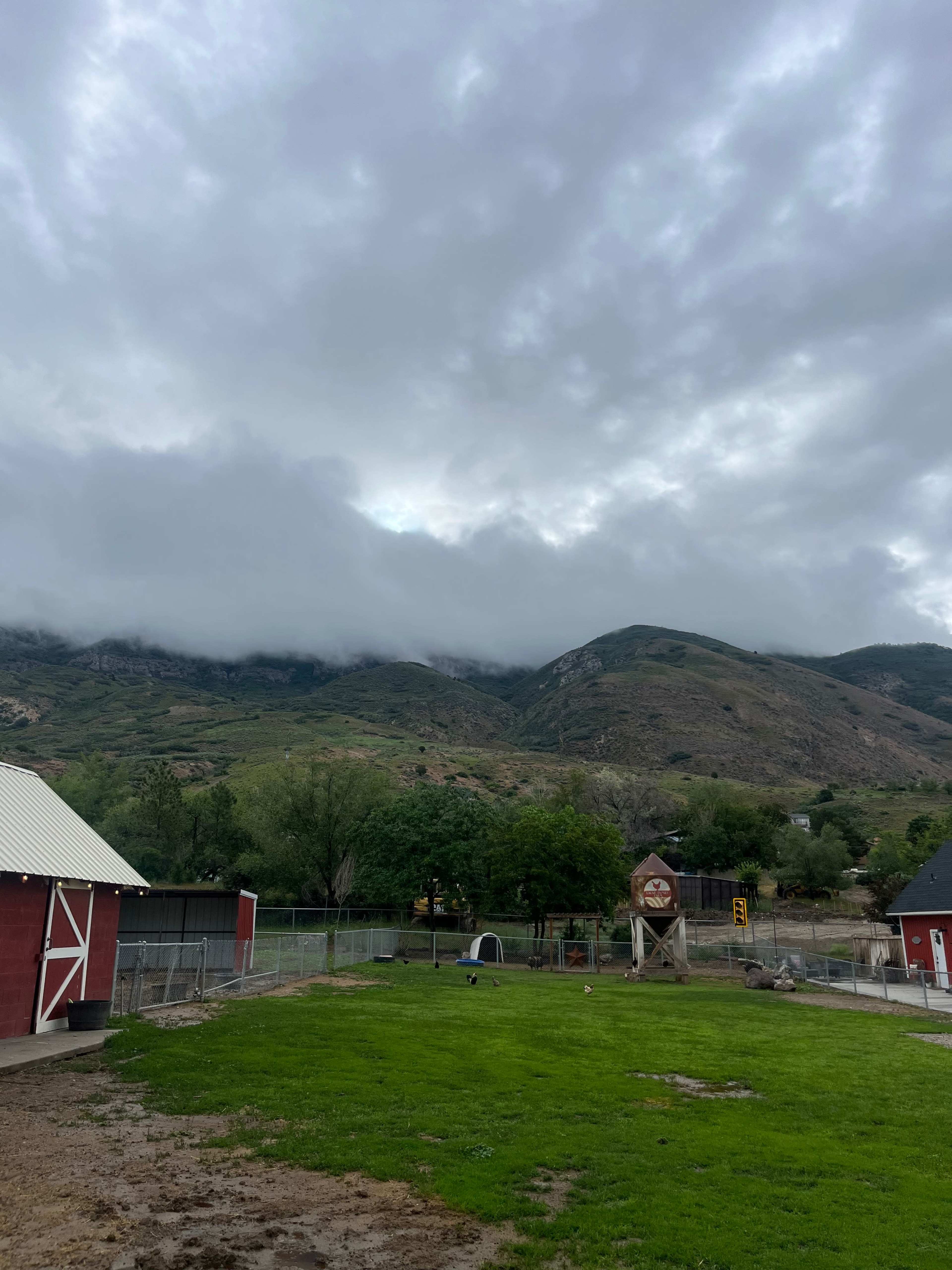 A farm scene features red barn structures in the foreground, with a backdrop of mountains shrouded in clouds.