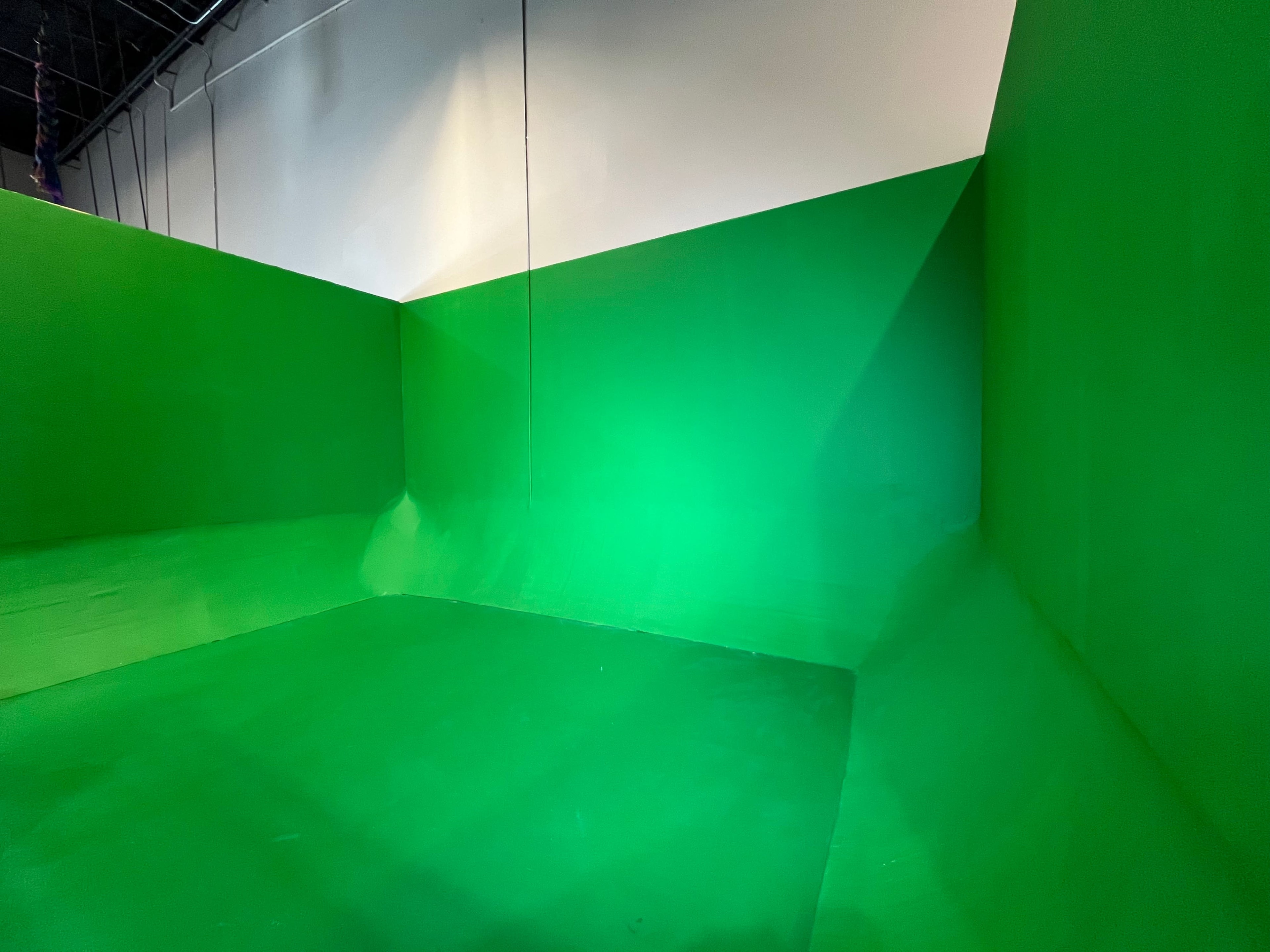 A green room with walls and a floor painted entirely in green, designed for chroma keying.