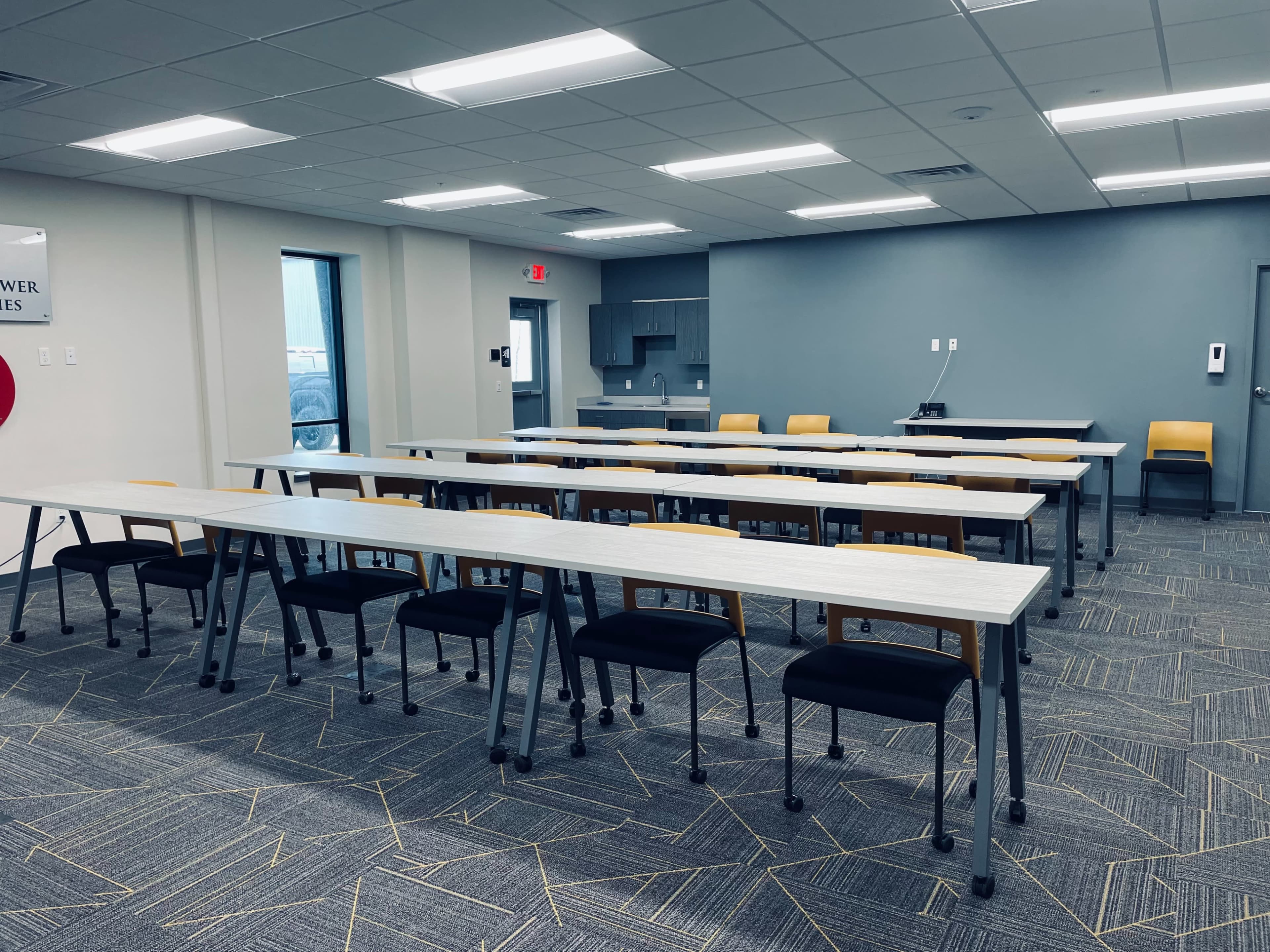 A modern classroom setup with several rows of tables and chairs arranged neatly in a well-lit space.