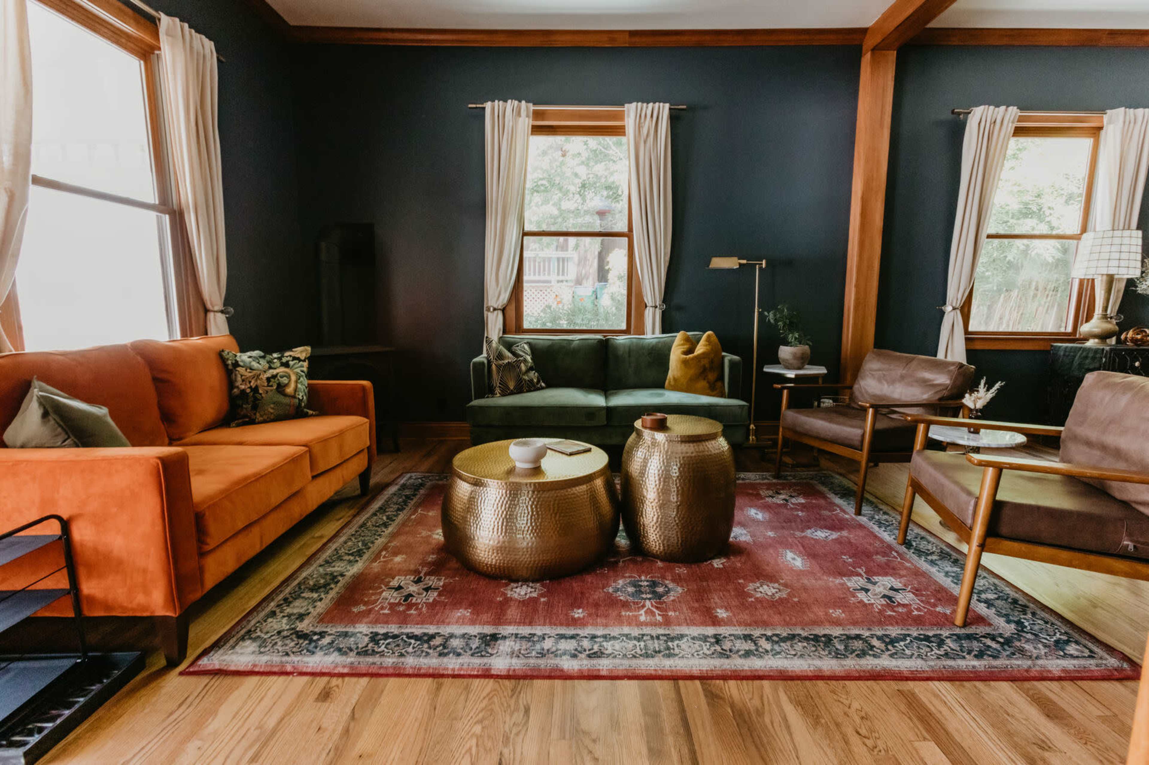 The living room features two sofas, a pair of armchairs, a central area rug, and bronze side tables arranged around a window.