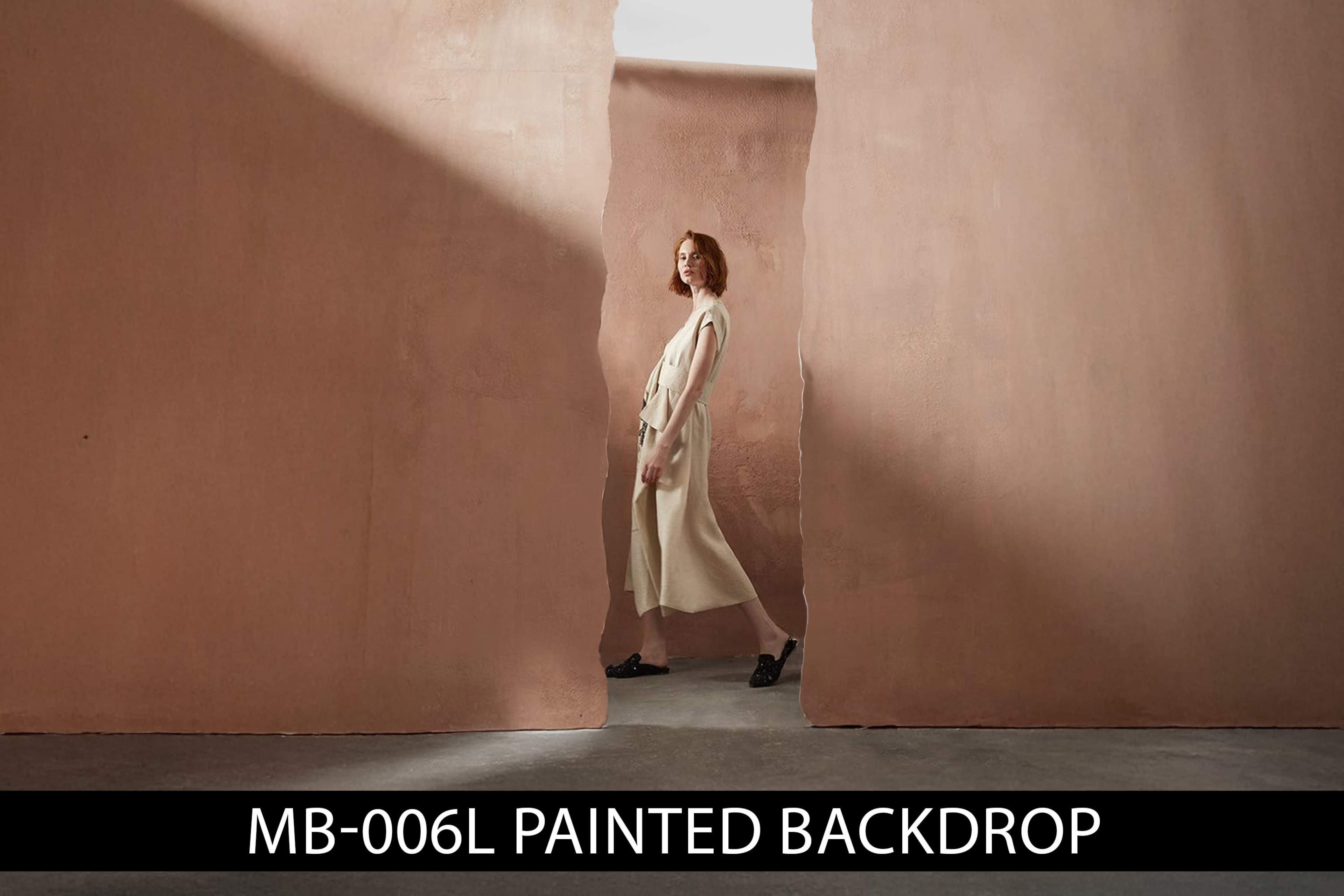 A model in a light-colored outfit stands between two large, painted walls in a minimalist setting.