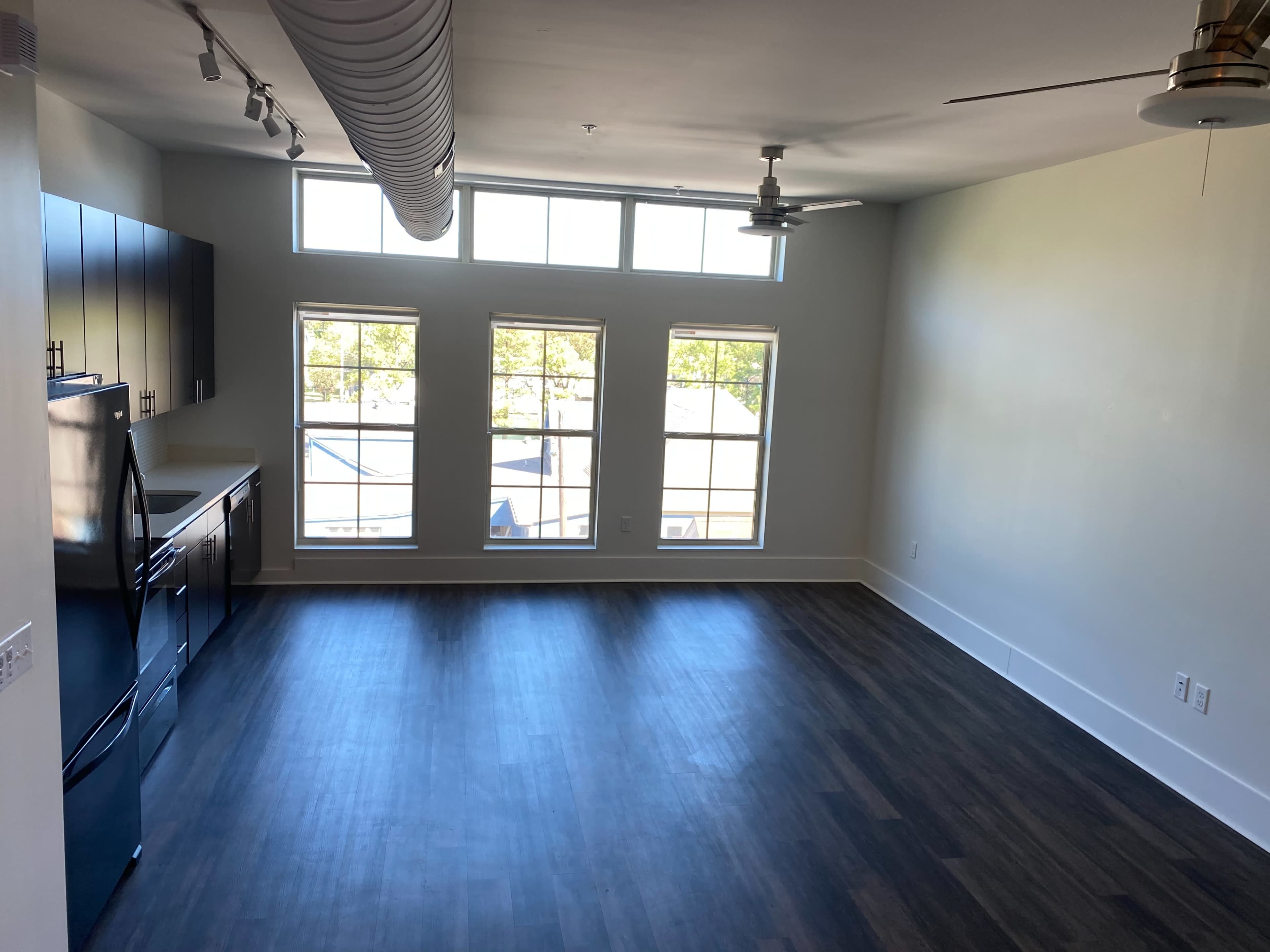 A spacious room features large windows and a kitchen area with modern appliances.