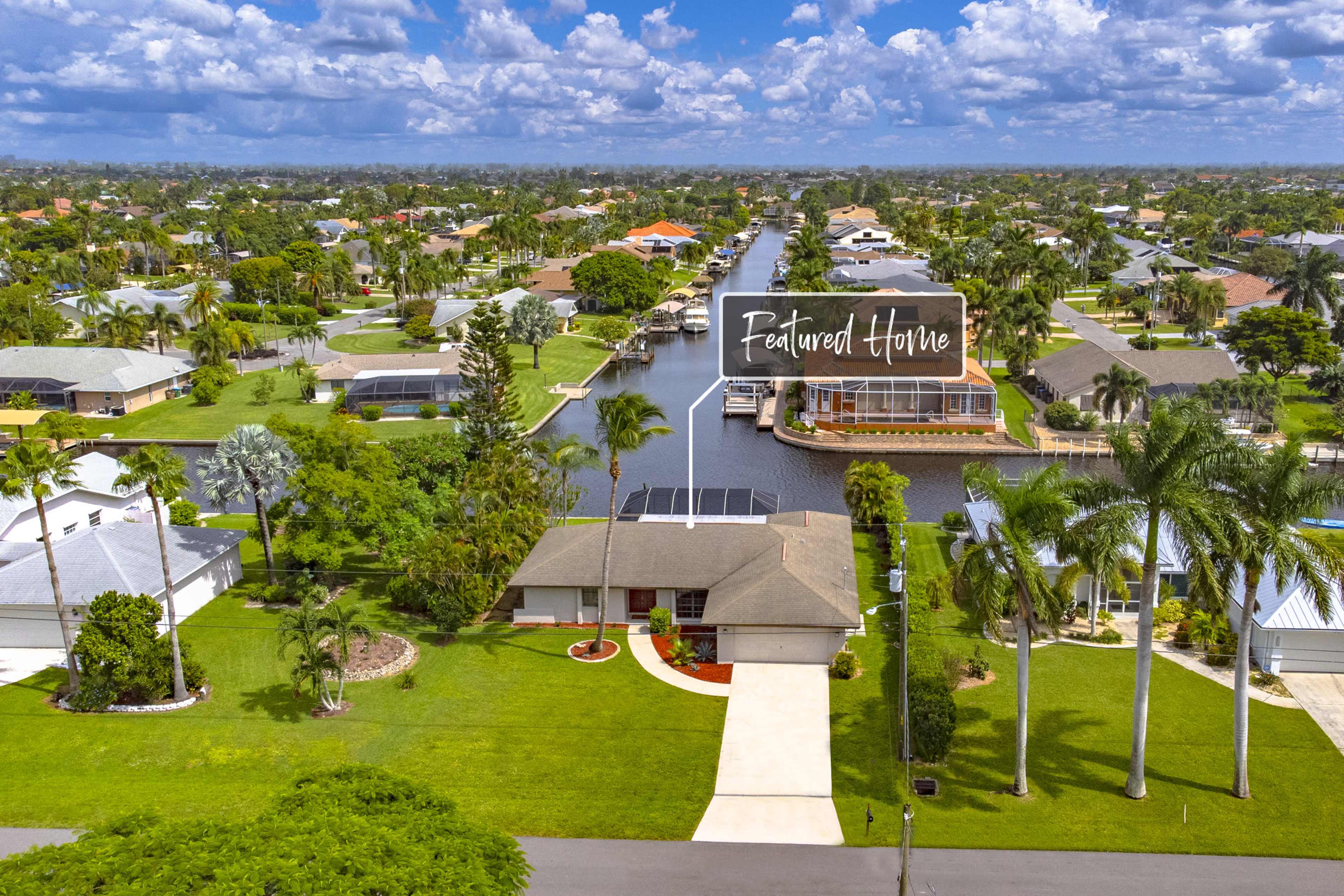 A suburban neighborhood with a waterfront property prominently labeled as "Featured Home" and surrounded by greenery and other houses.