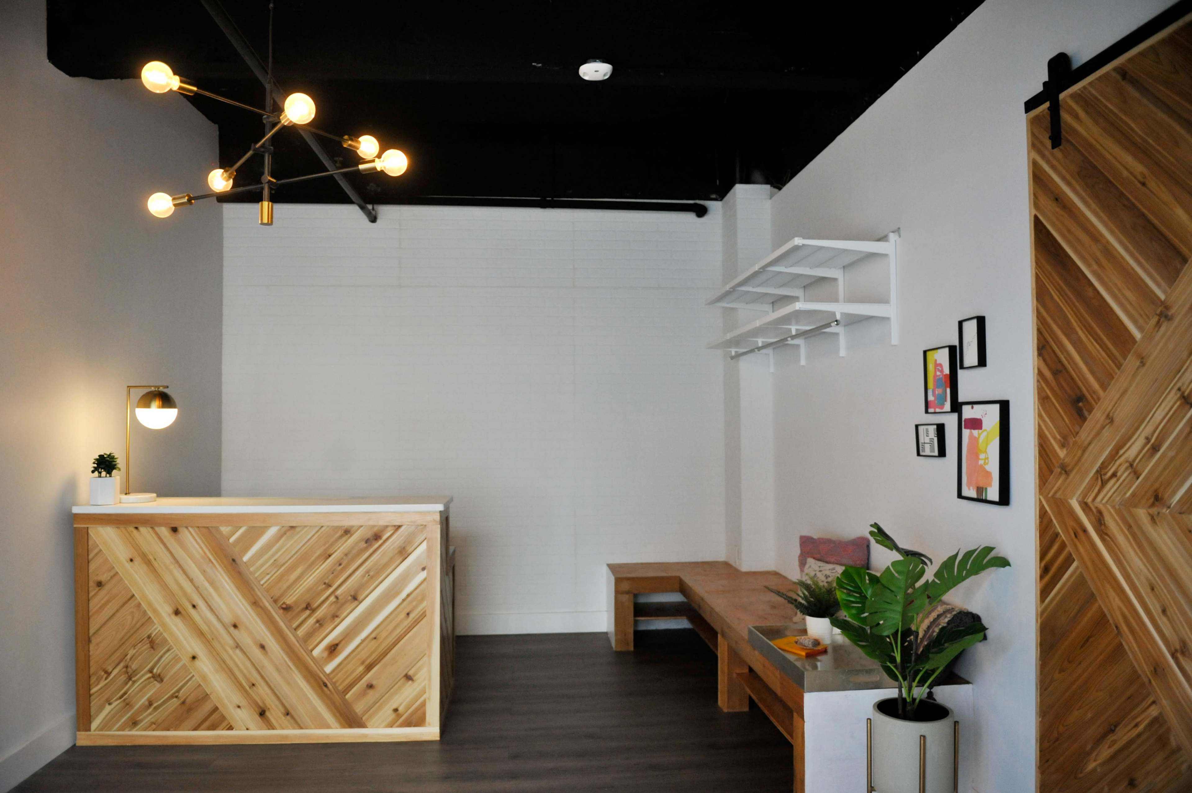 A modern reception area featuring a wooden reception desk, a bench, and minimalist decor against a light-colored wall.