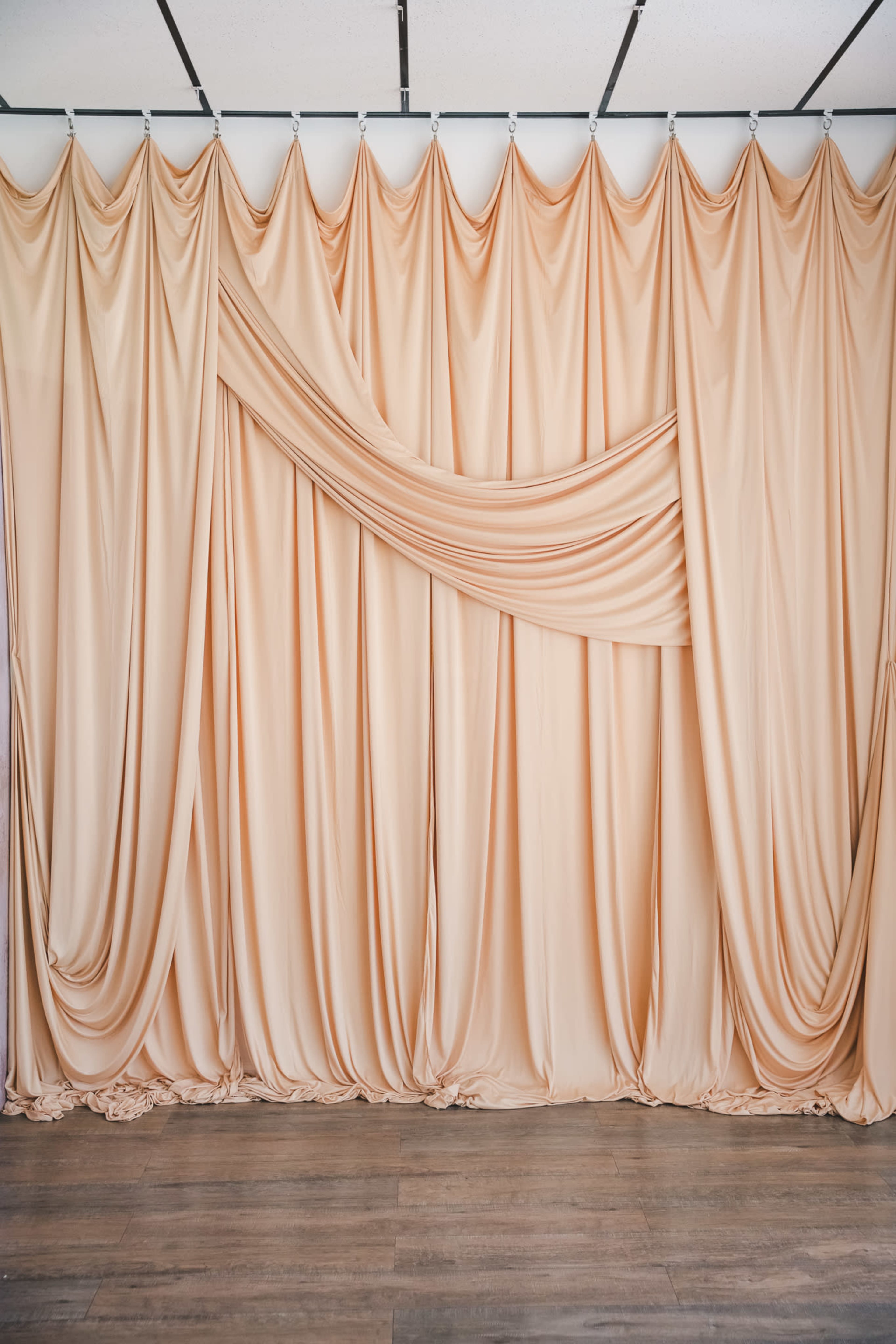 A peach-colored fabric backdrop with draped folds hangs from a ceiling.