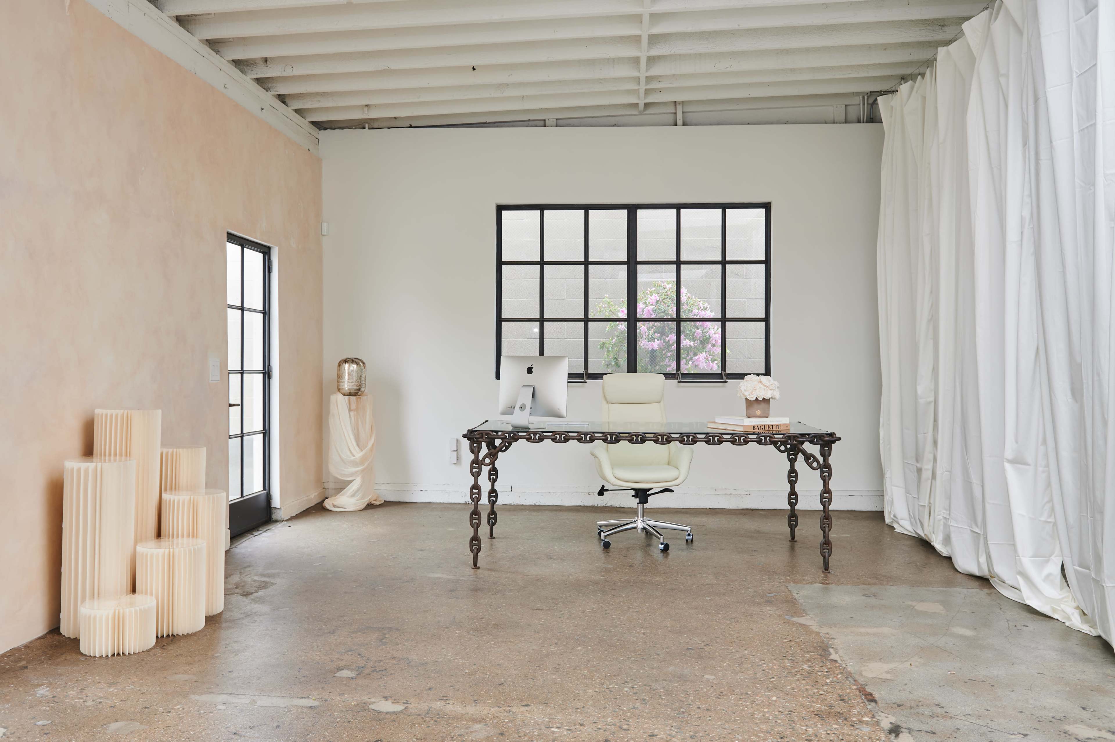 A spacious office with a desk and chair, a computer, and decorative elements in a minimalist, airy setting.