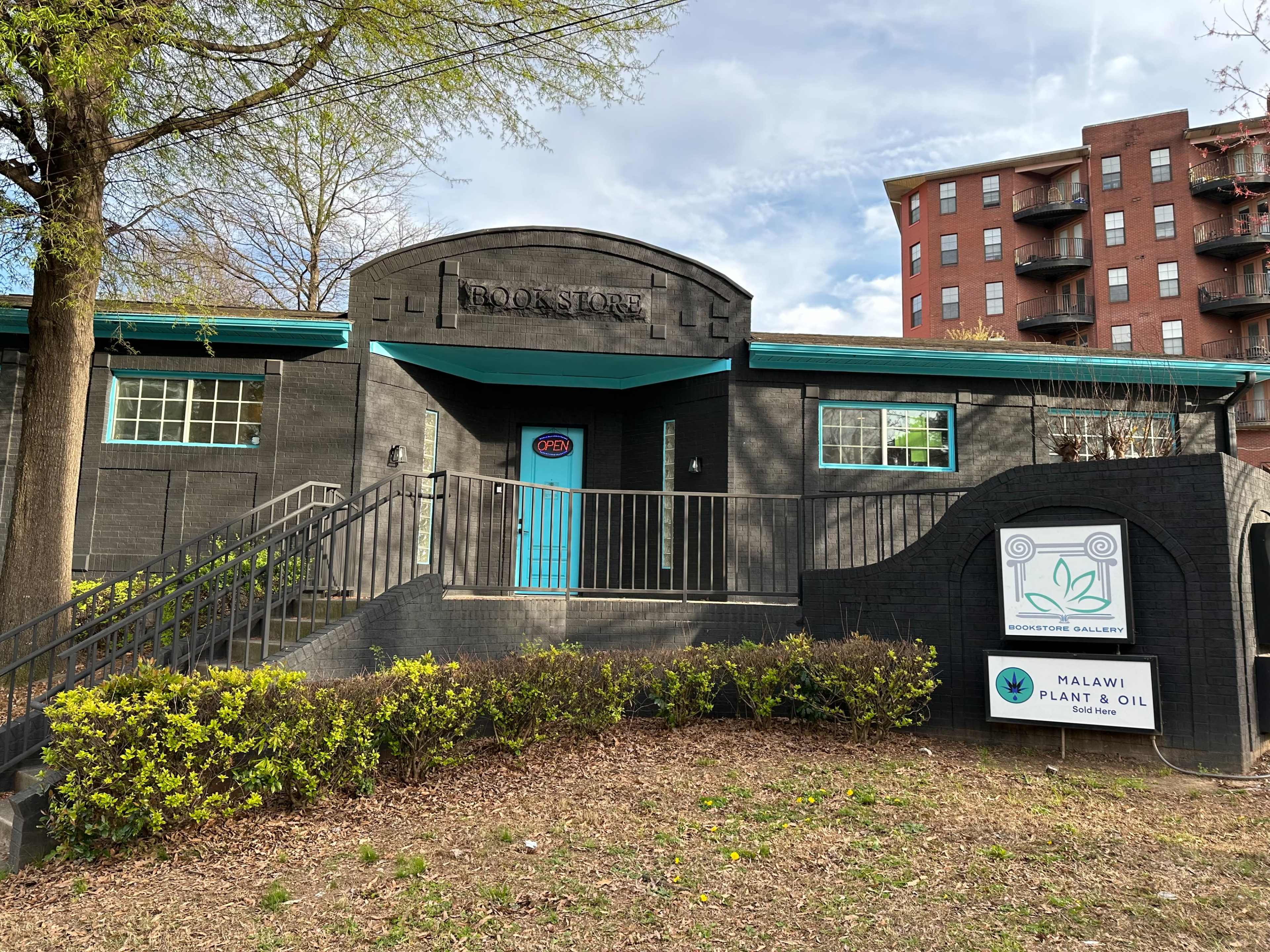 A black building labeled "BOOK STORE," featuring a blue door and a sign for "MALAWI PLANT & OIL" in front.
