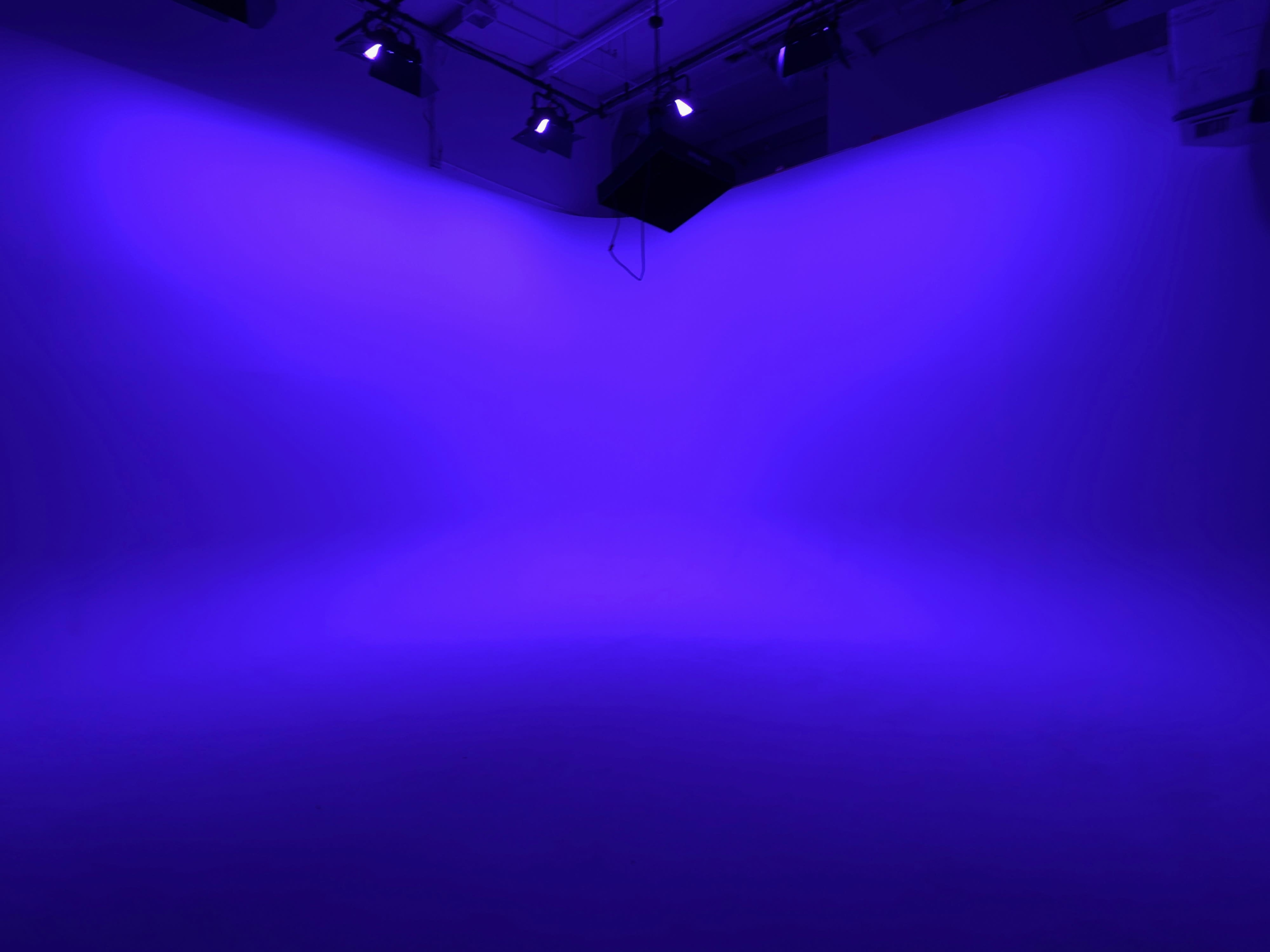 The image shows a studio space illuminated by purple lighting, creating a gradient effect on the walls and floor.