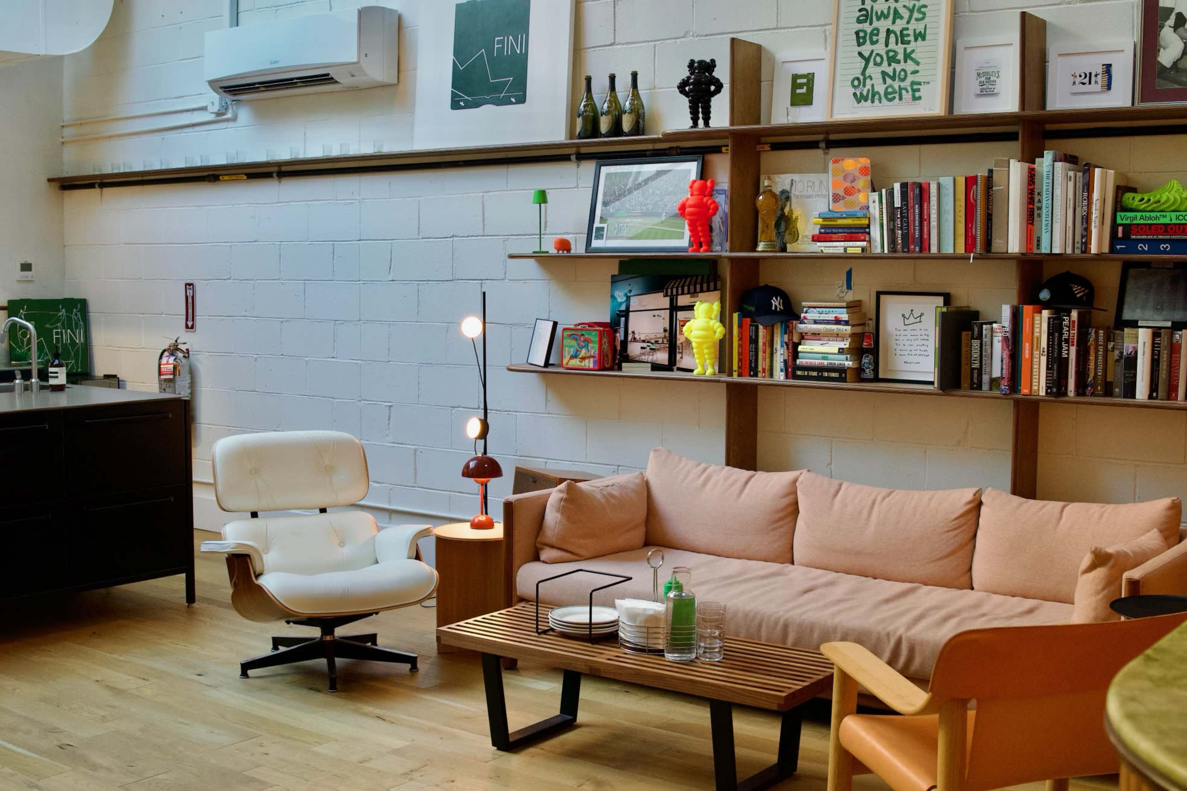 A modern living room with a sofa, a wooden coffee table, bookshelves filled with books and decorative items, and various furniture pieces.