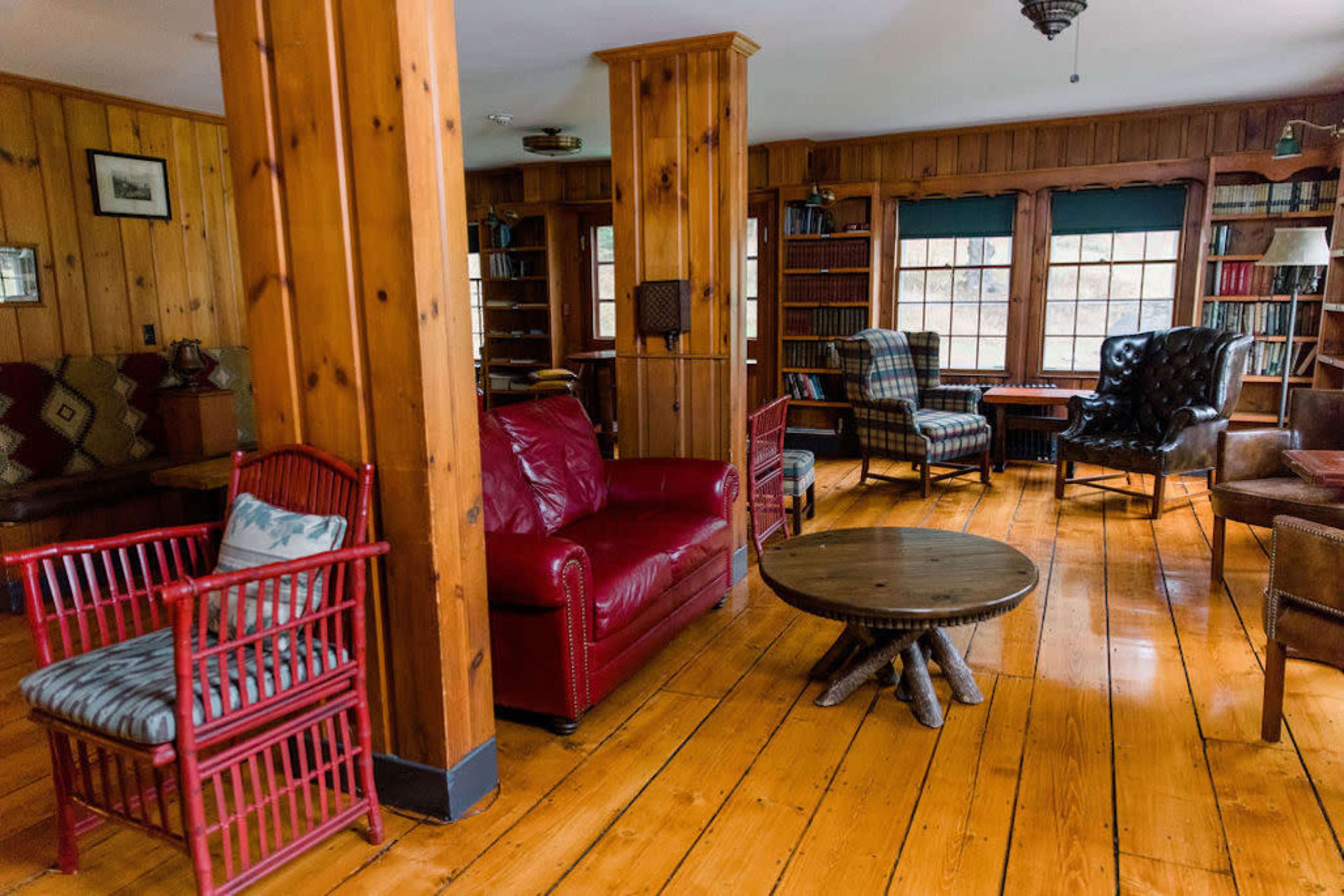 A cozy living room with wooden walls, several comfortable seating options, and a round wooden coffee table.