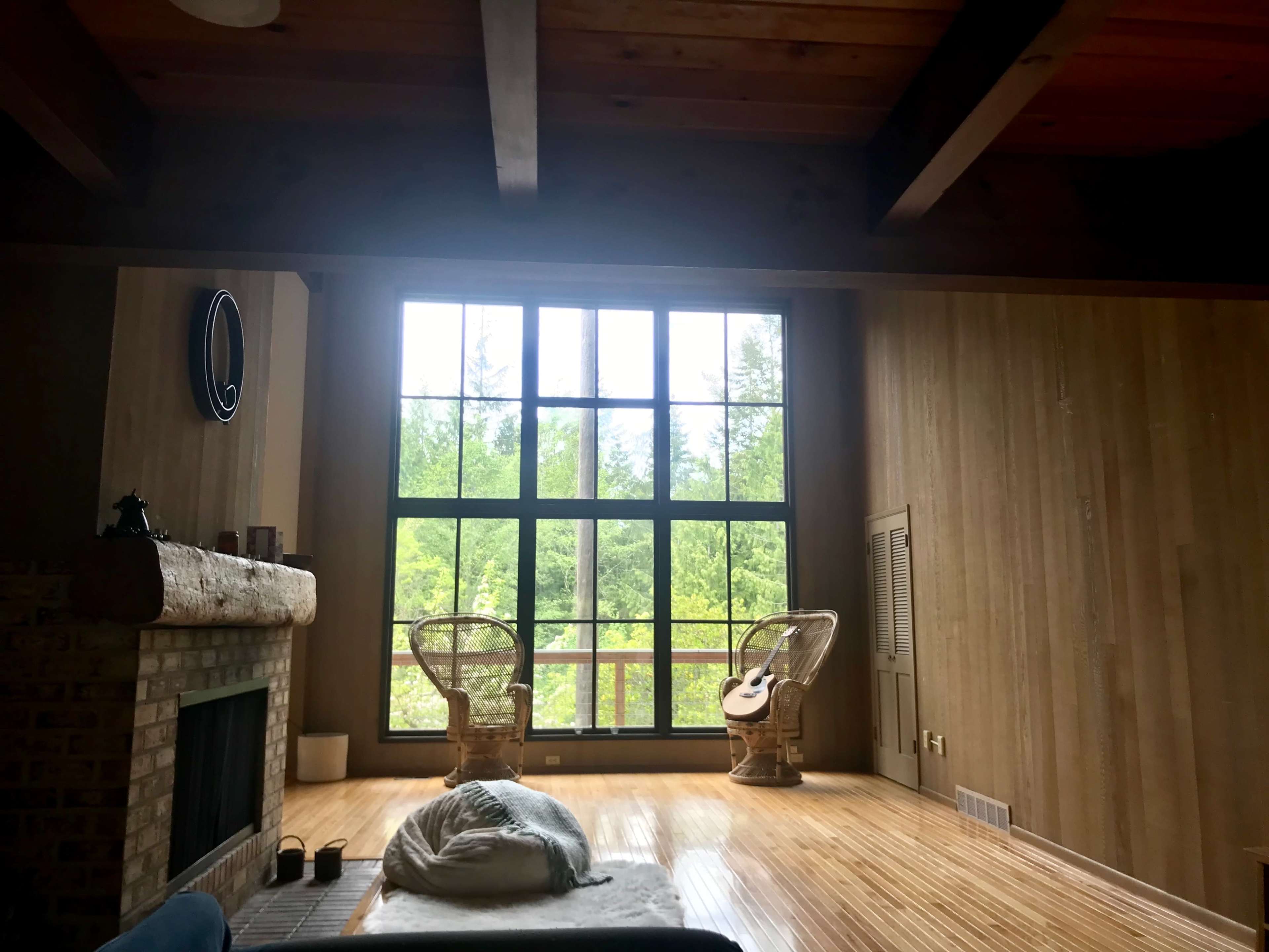 A spacious room features two wicker chairs positioned by a large window overlooking a green landscape.