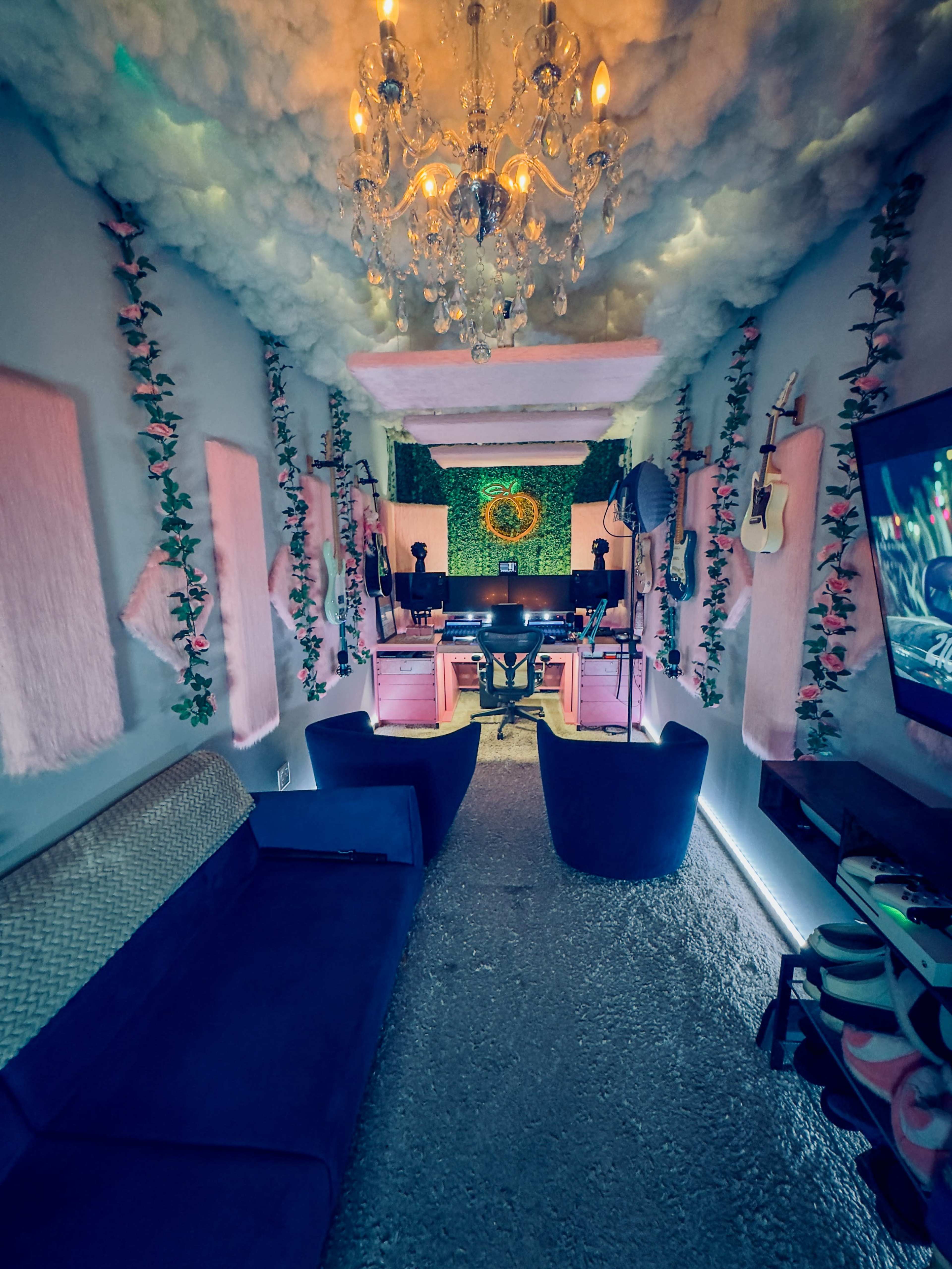 A cozy music studio with floral decorations, a chandelier, and a piano at the center surrounded by musical instruments and a comfortable seating area.