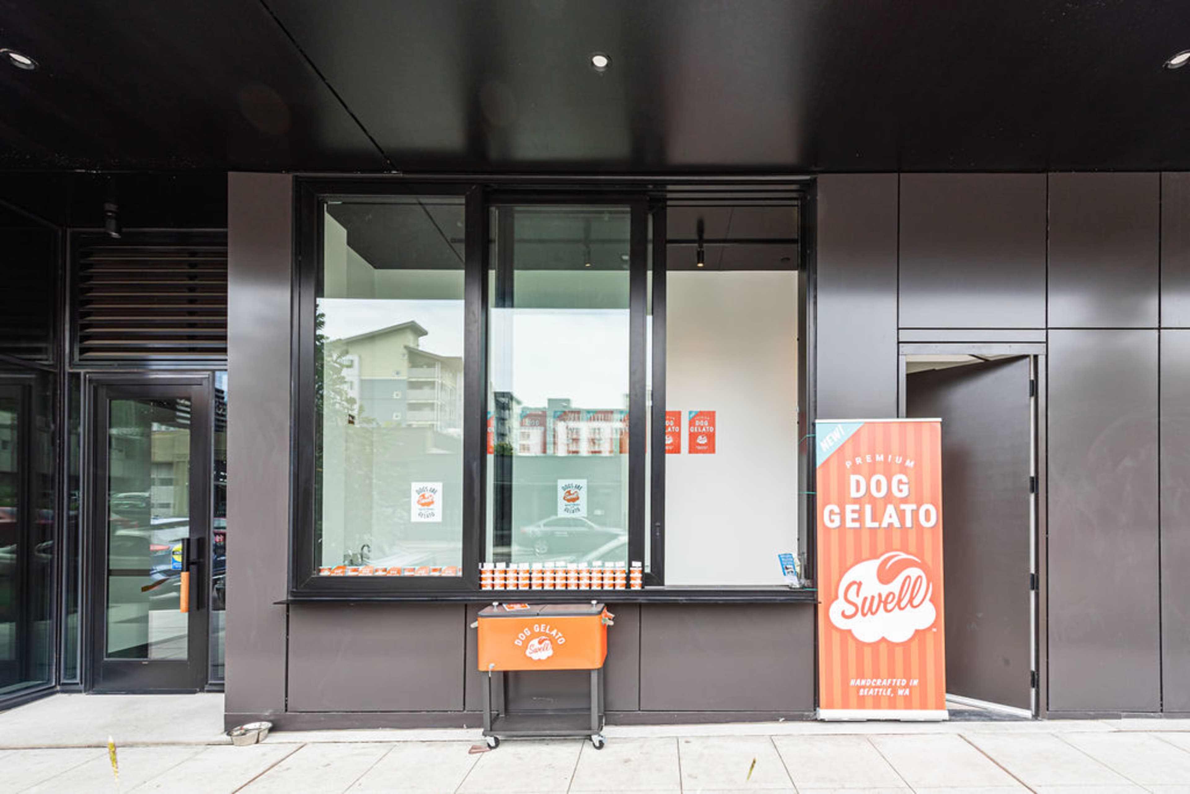 The exterior of a modern storefront features large windows, a sign for "Dog Gelato," and a small serving cart outside.