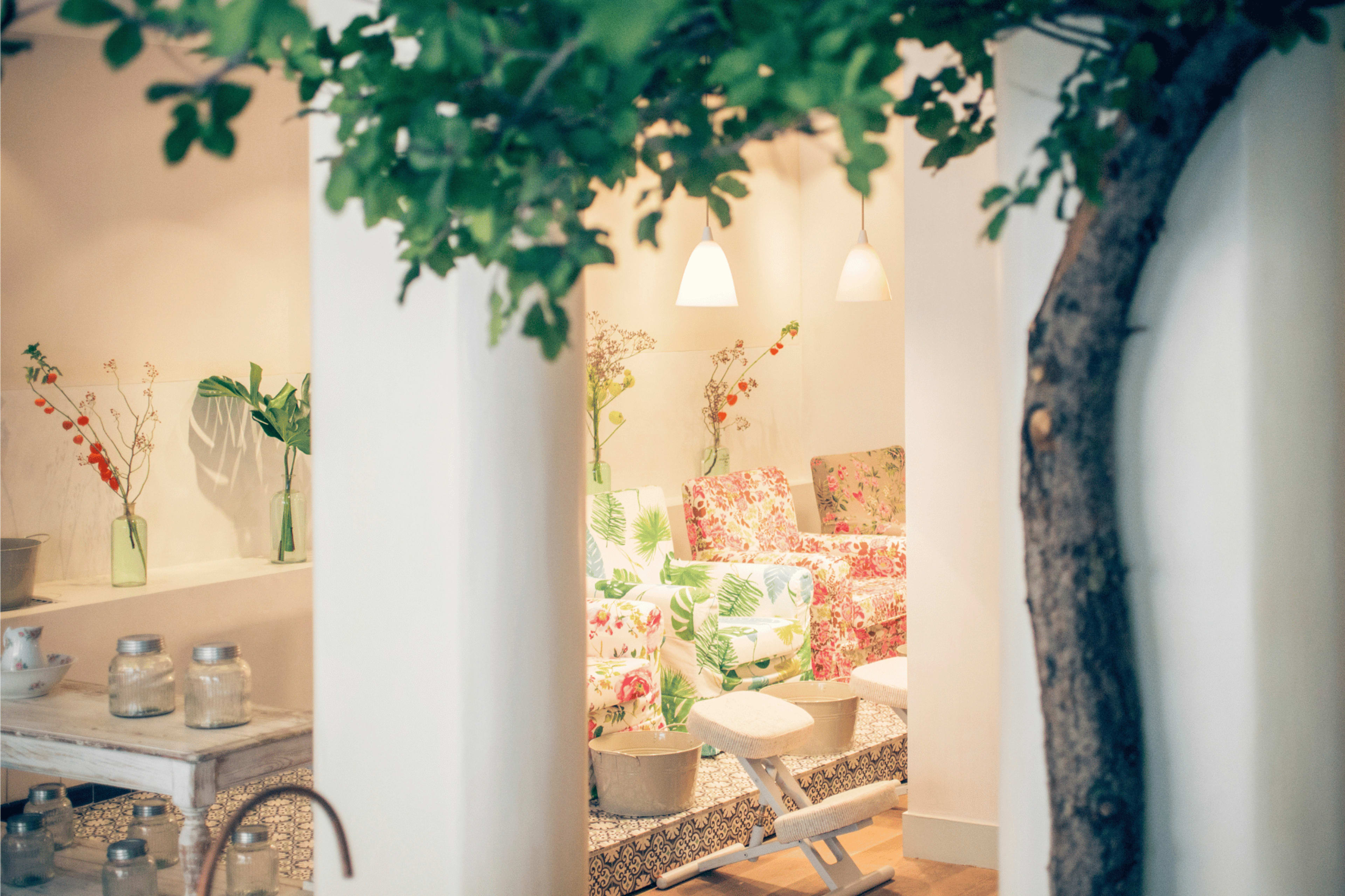 A brightly decorated interior space featuring floral-patterned furniture, potted plants, and soft lighting.