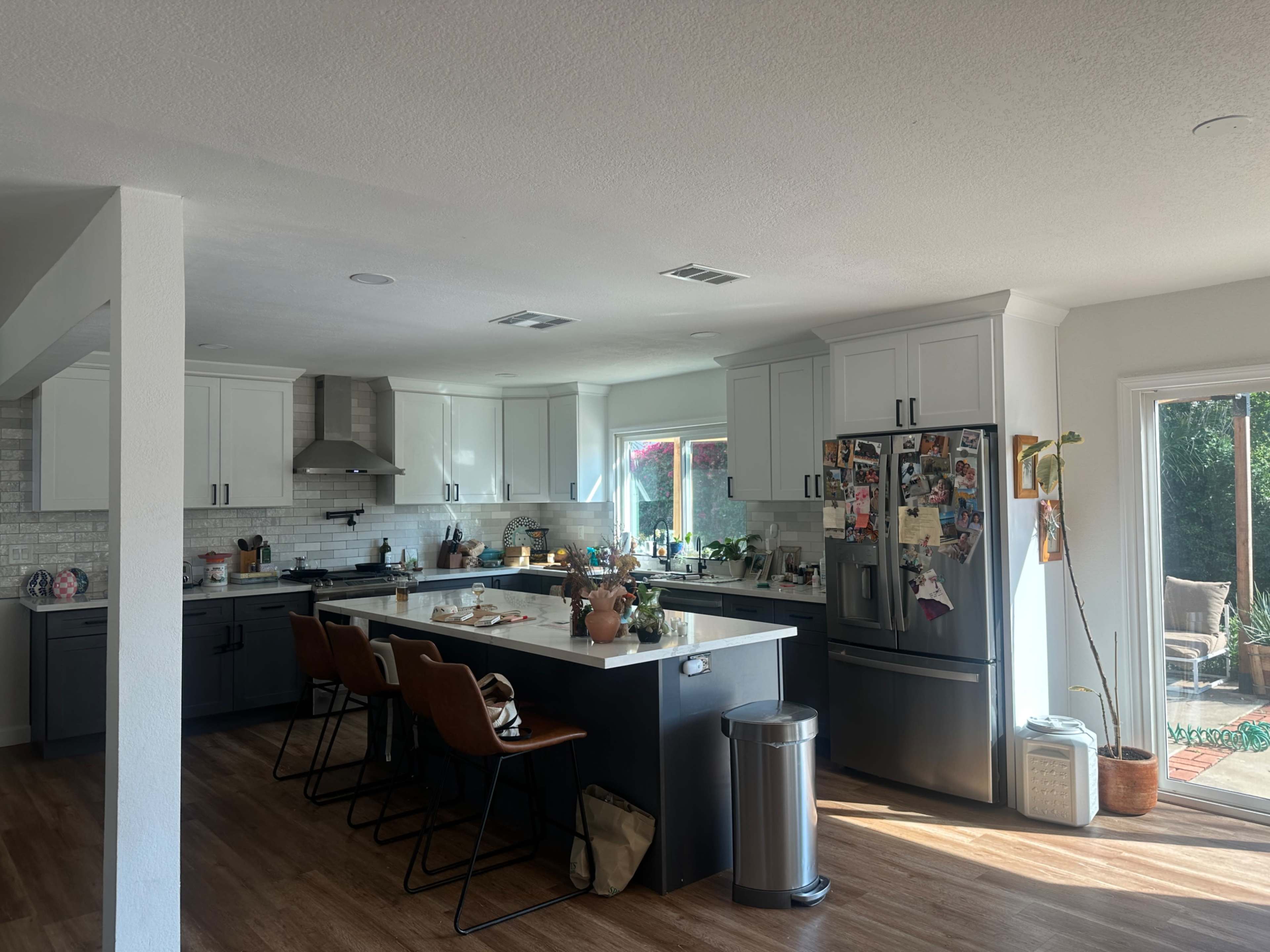 The image features a modern kitchen with a large island, gray cabinetry, and a mix of appliances, along with several items and decor on the counter.