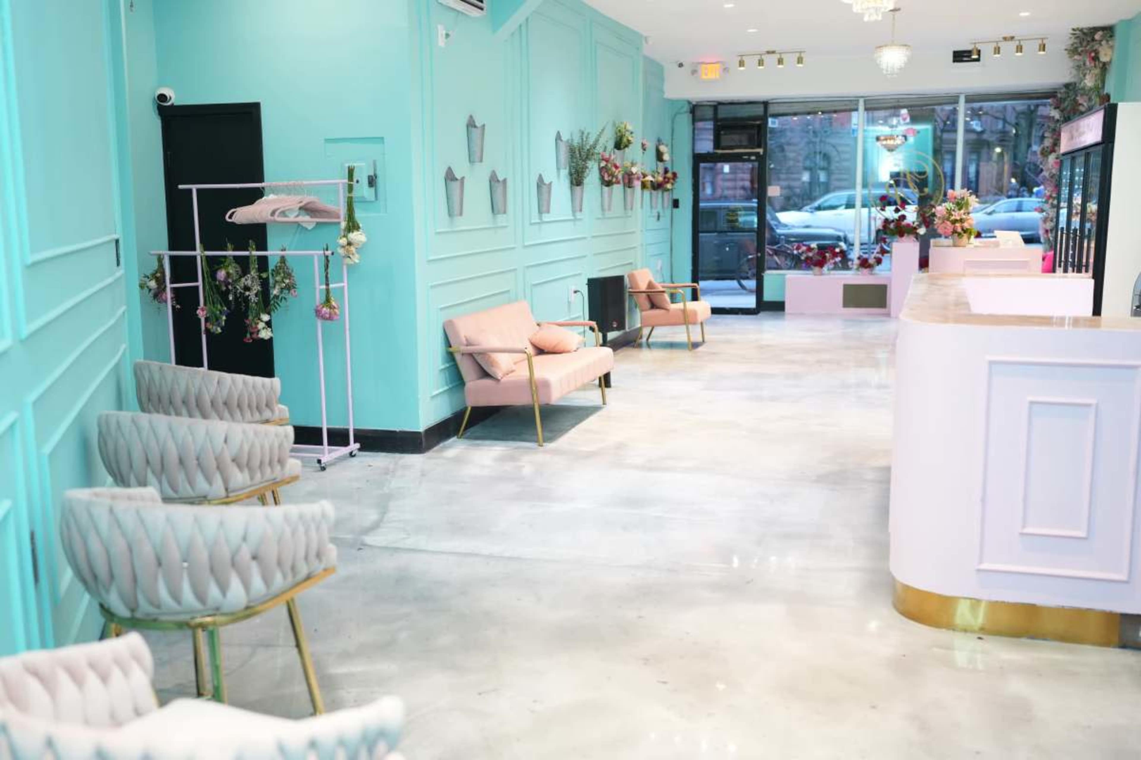 The image shows a bright interior of a modern salon with mint green walls, pink furnishings, and large windows allowing natural light to enter.