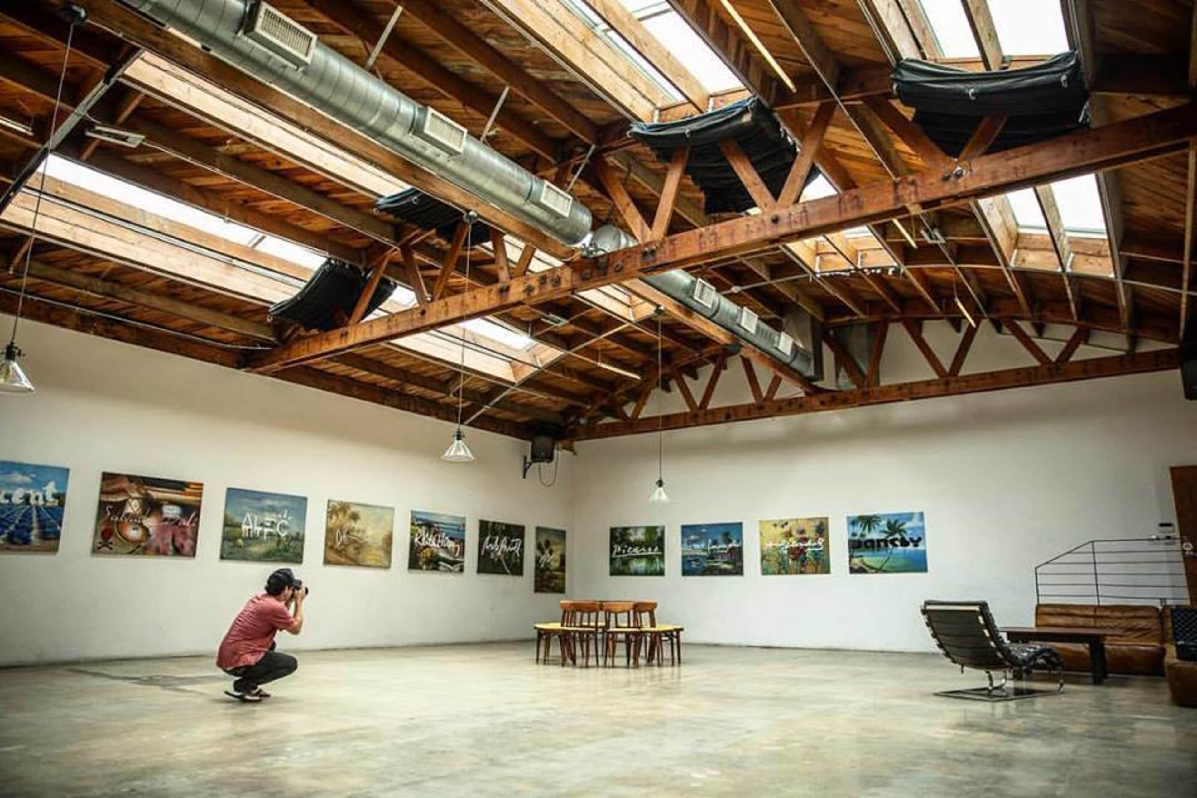 A photographer captures an empty art gallery featuring large framed images on the walls and sparse furniture in the center.