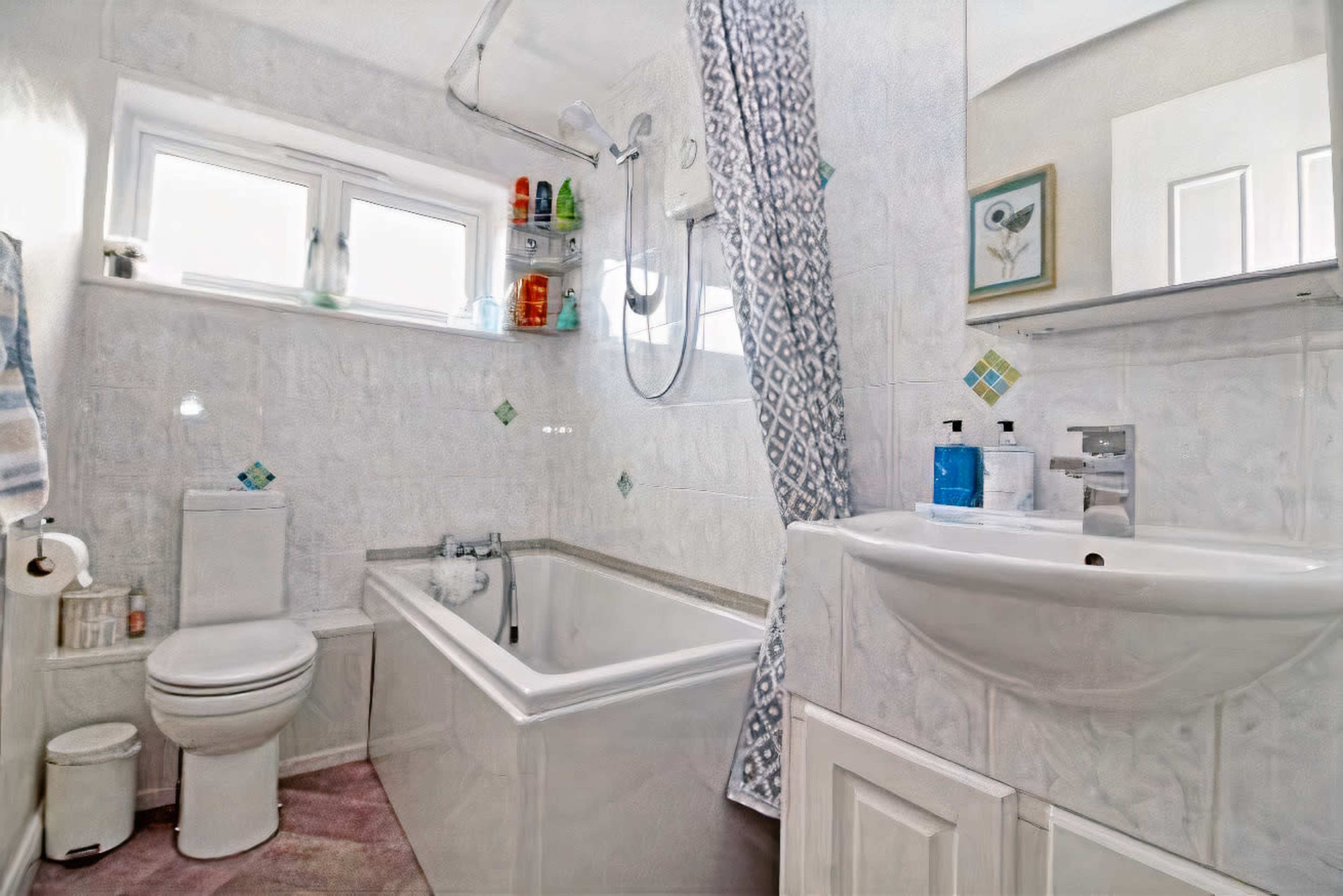The image shows a compact bathroom featuring a bathtub, a showerhead above, a toilet, and a sink with a mirror.