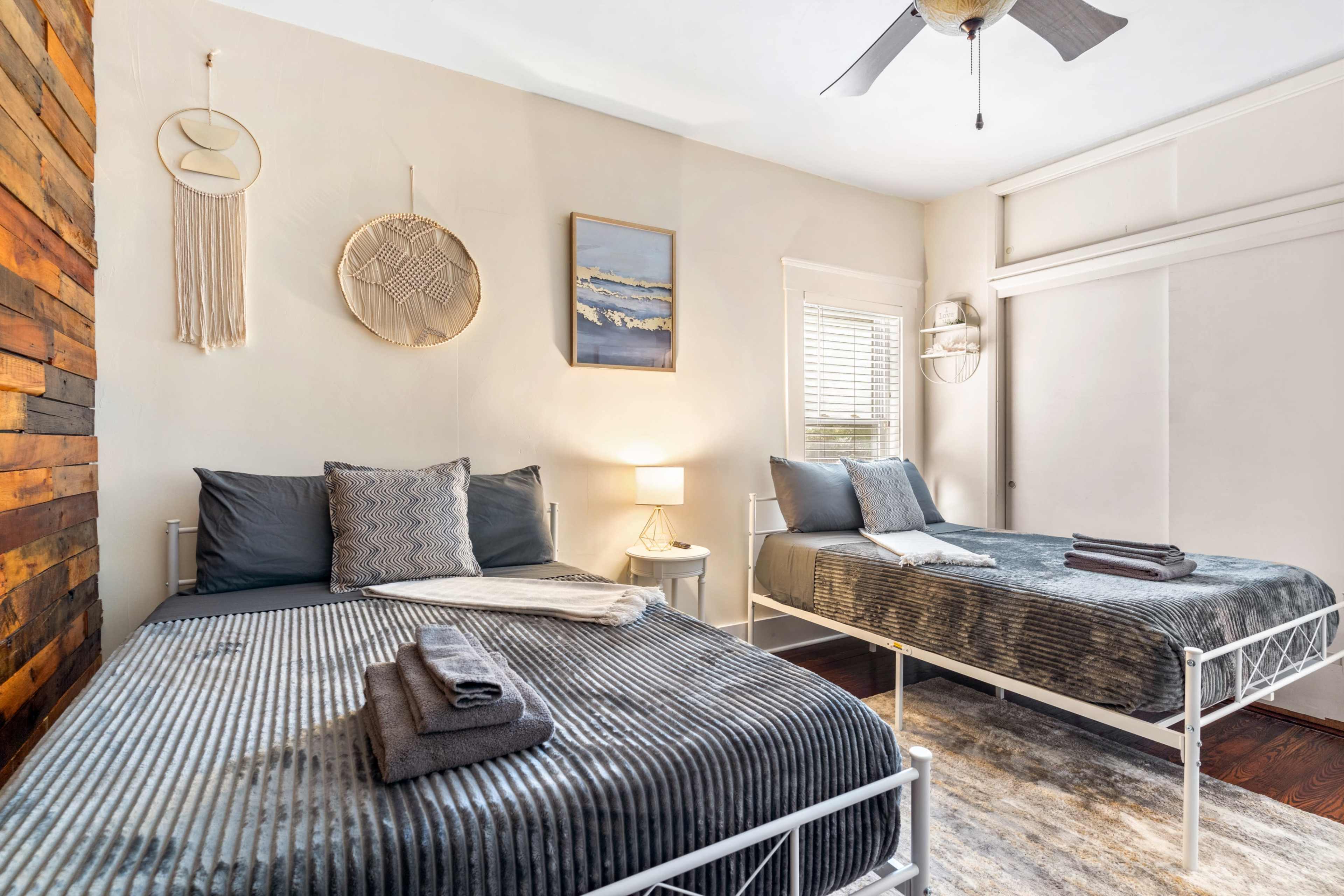 A cozy bedroom with two beds, a wooden accent wall, and decorative wall hangings.