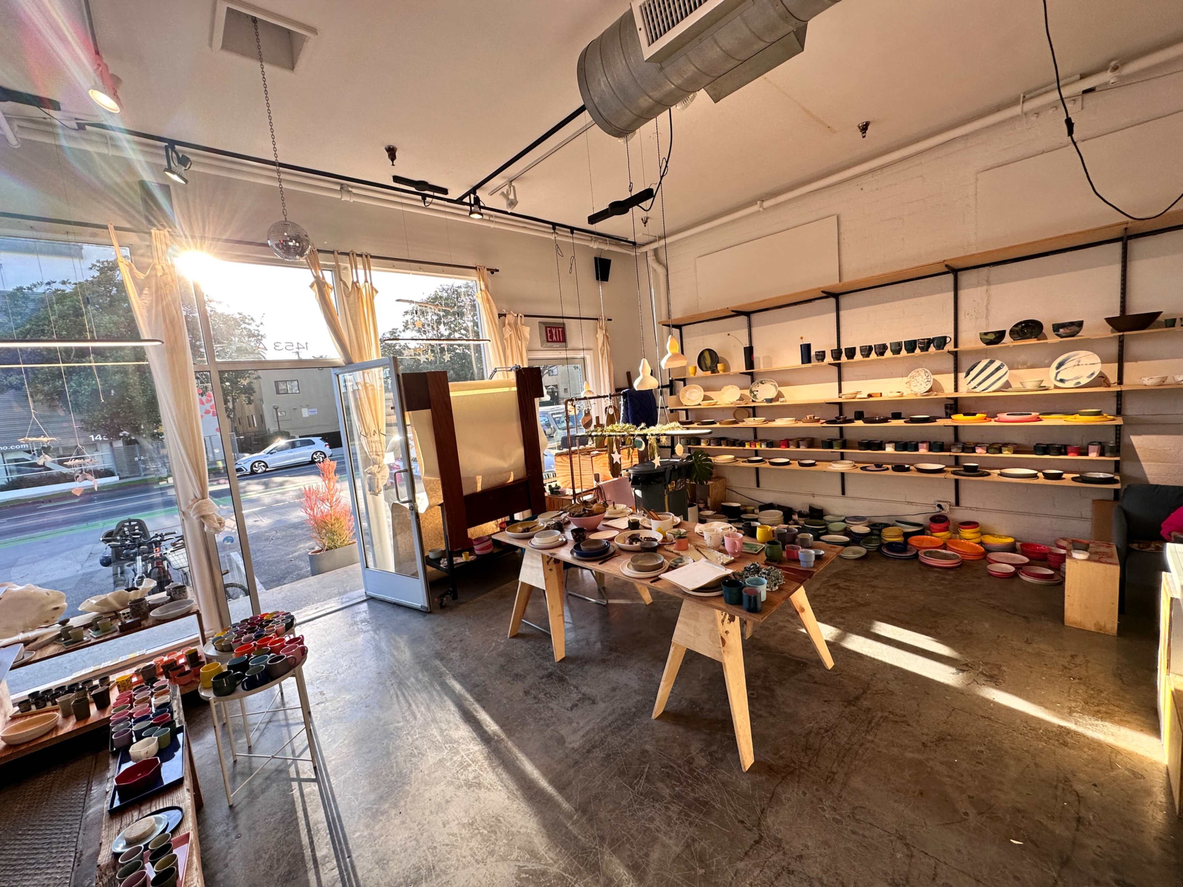 The image shows a well-lit store interior featuring a variety of colorful dishes and pottery arranged on tables and shelves.