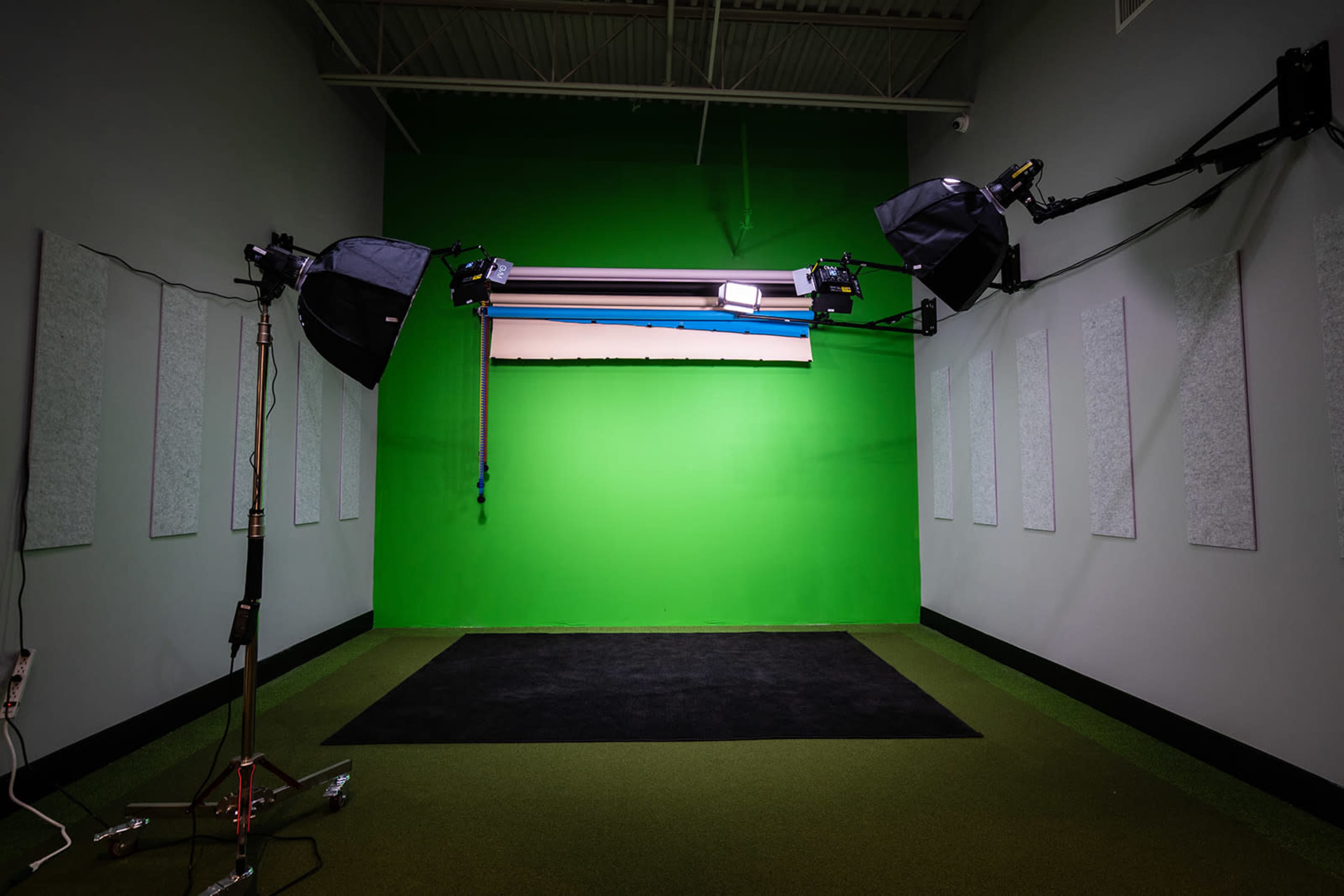 The image shows a green screen studio equipped with lighting fixtures and soundproof panels on the walls.
