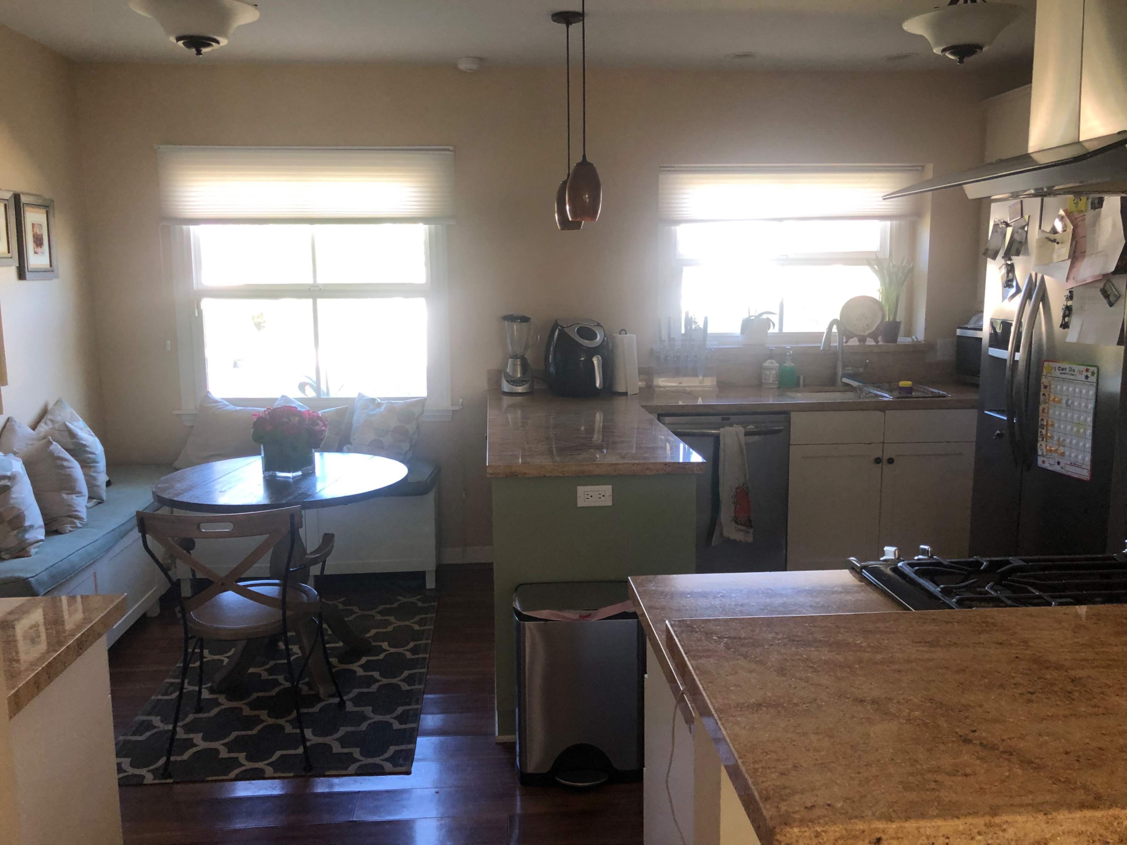 A kitchen and dining area featuring a round table with chairs, a countertop with appliances, and a sofa against the wall.