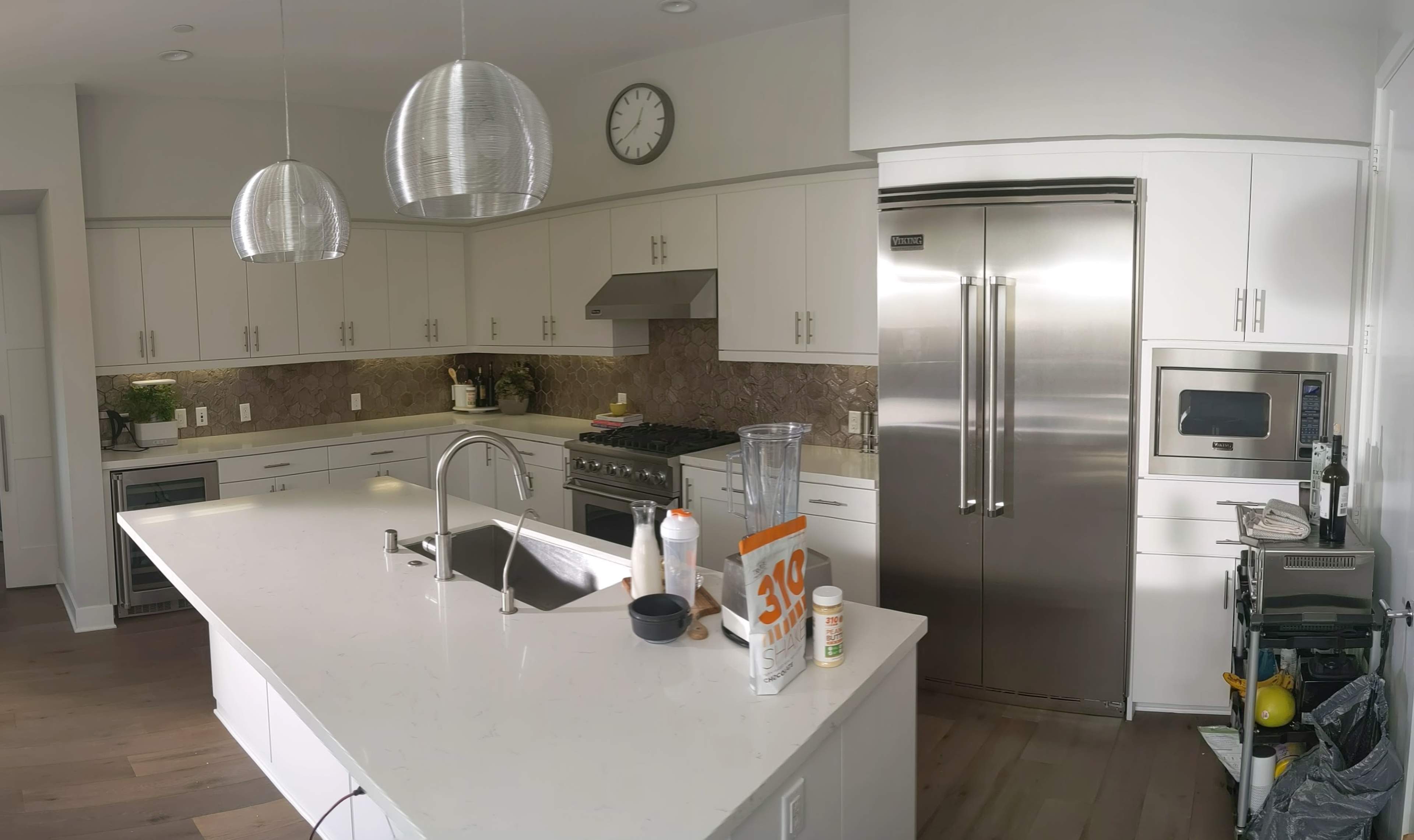 The image shows a modern kitchen with a large island, stainless steel appliances, and ample cabinetry.