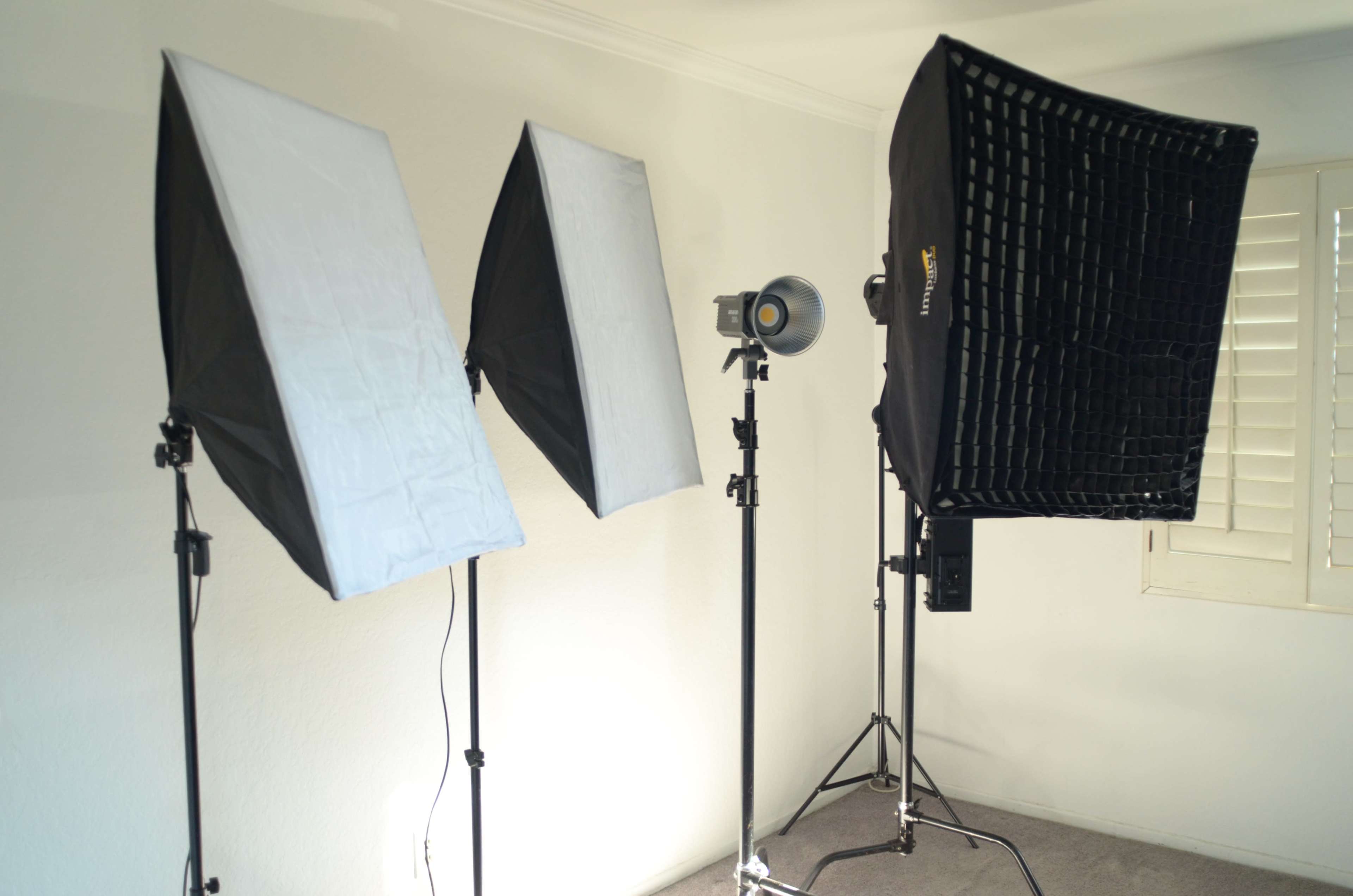 Three studio lighting setups arranged in a room with white walls and carpet.