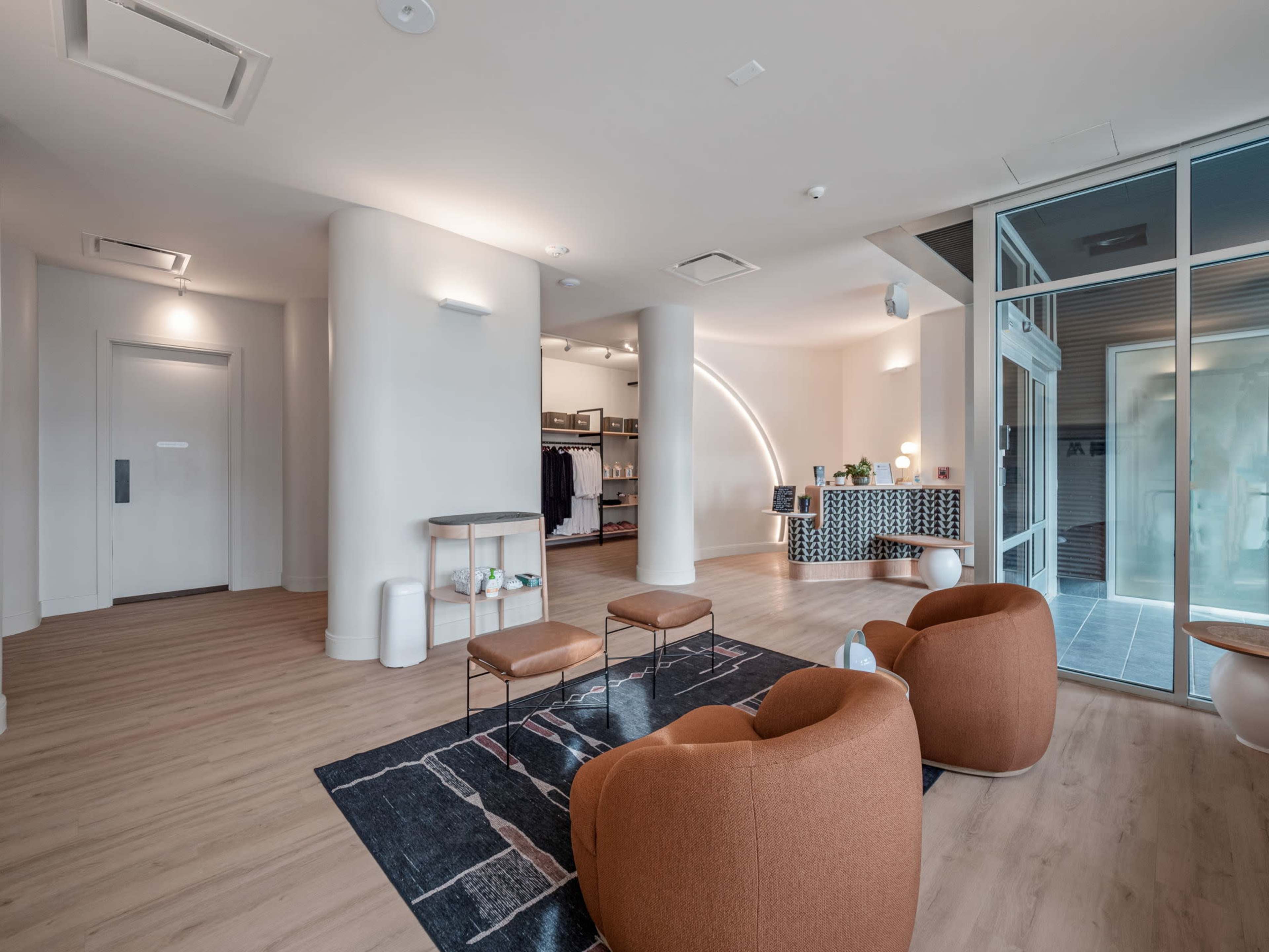 A modern lobby with curved seating, wooden floors, and a check-in area featuring a patterned desk.