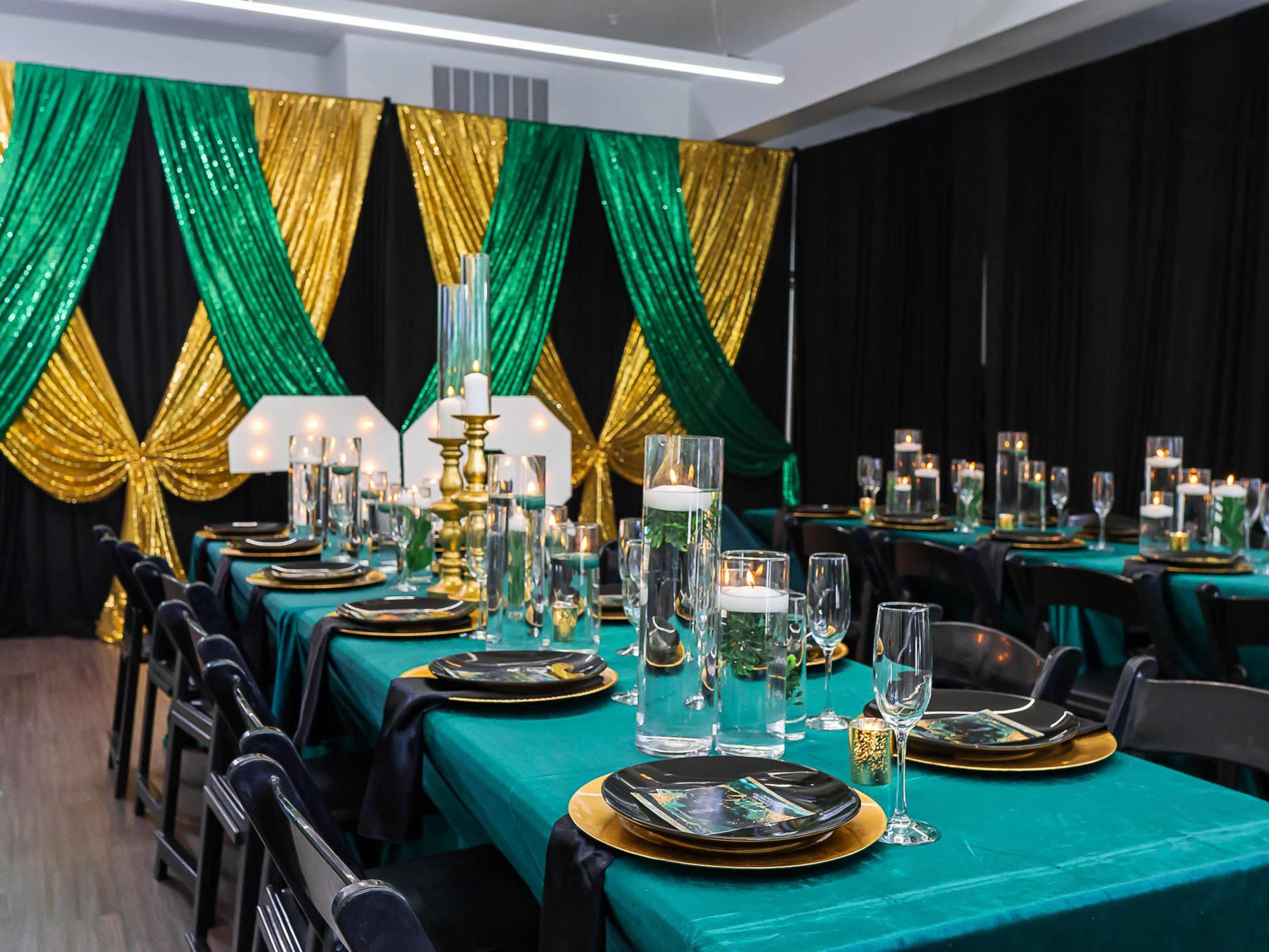 The image shows a decorated banquet room with emerald green and gold drapes, elegantly set dining tables, and various decorative candle displays.