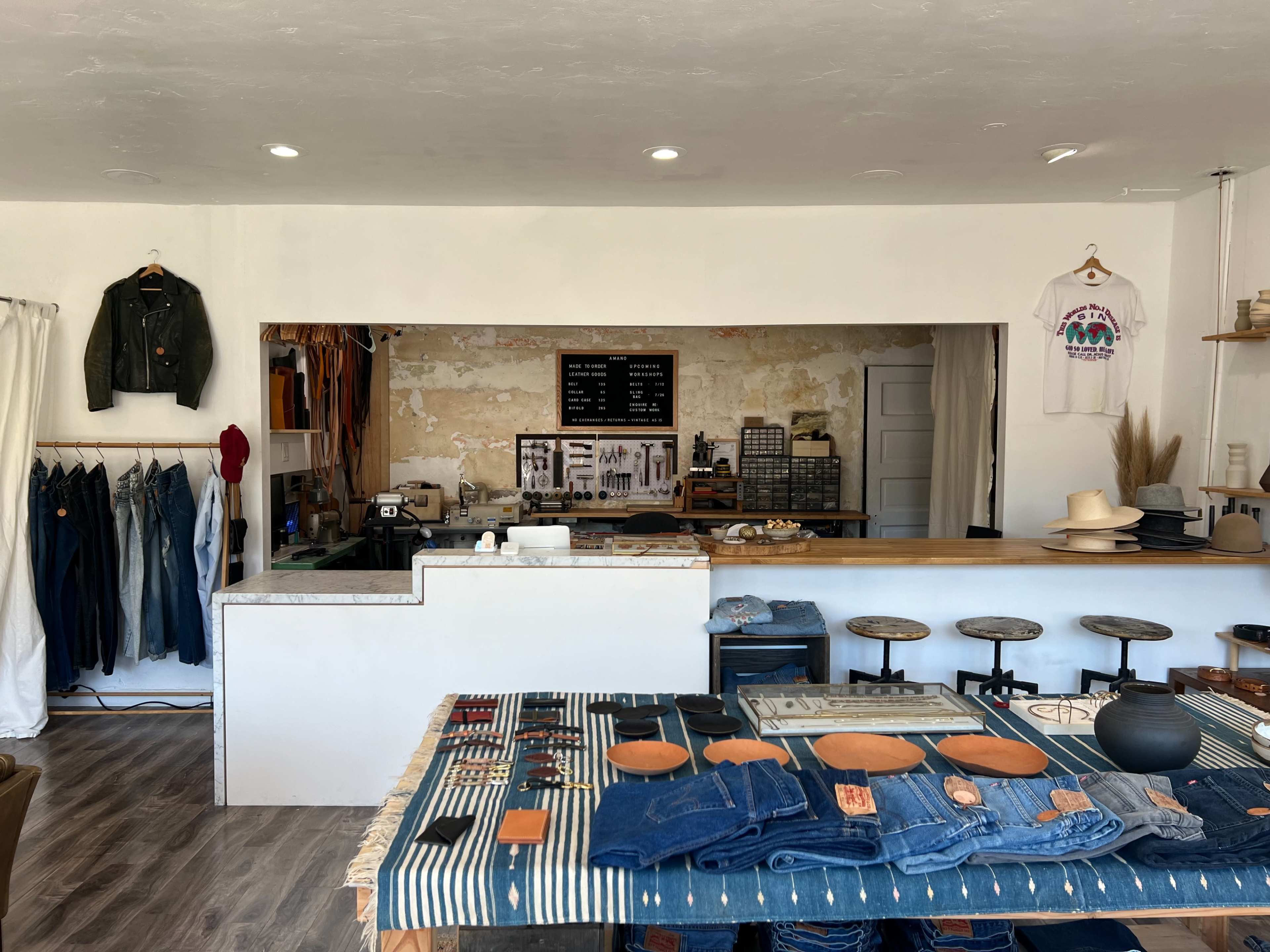 A boutique interior featuring a wooden counter, shelves with clothing and accessories, and a neatly arranged display of denim jeans on a table.
