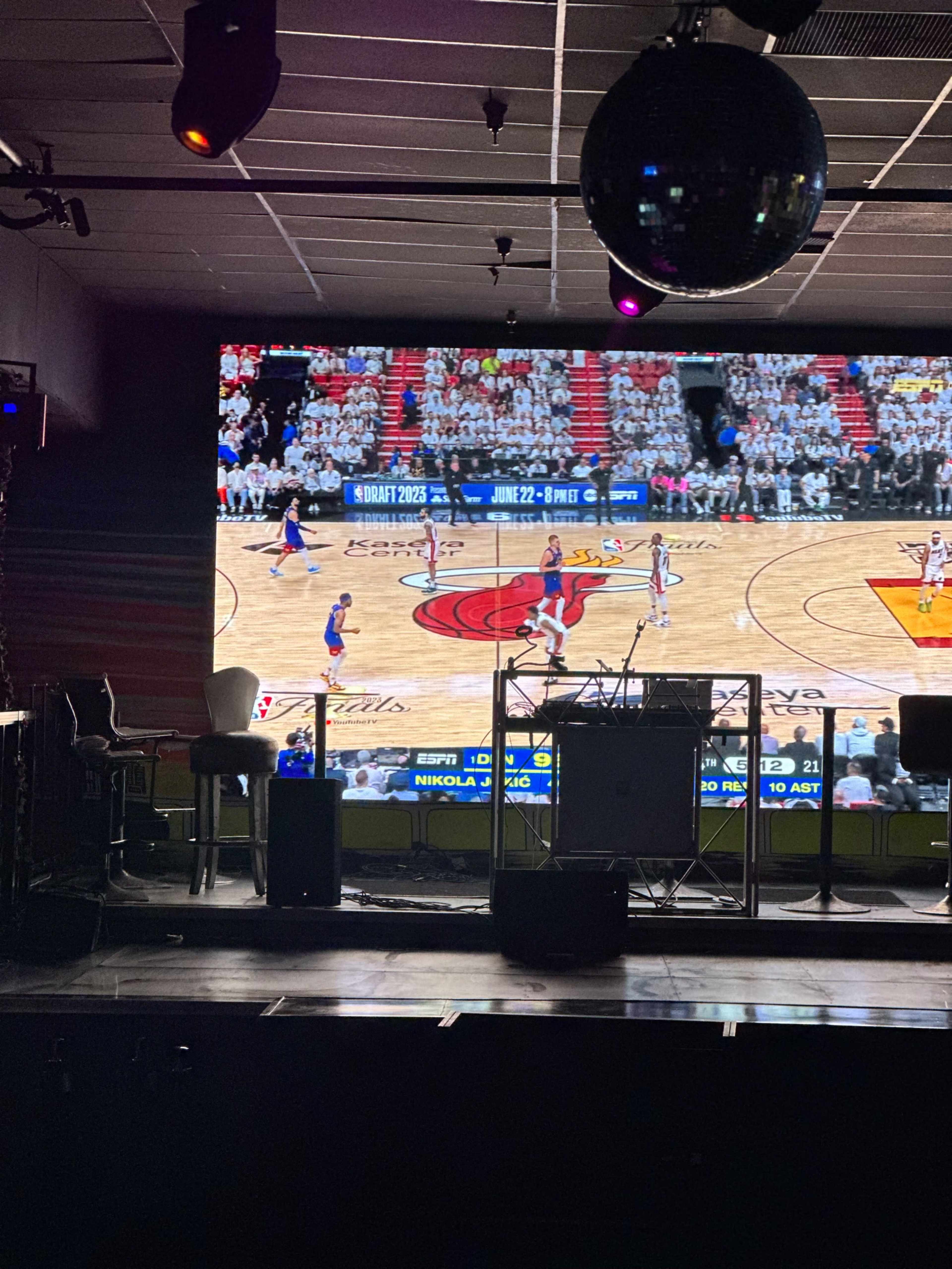 A large screen displays a basketball game with players in action on a court.