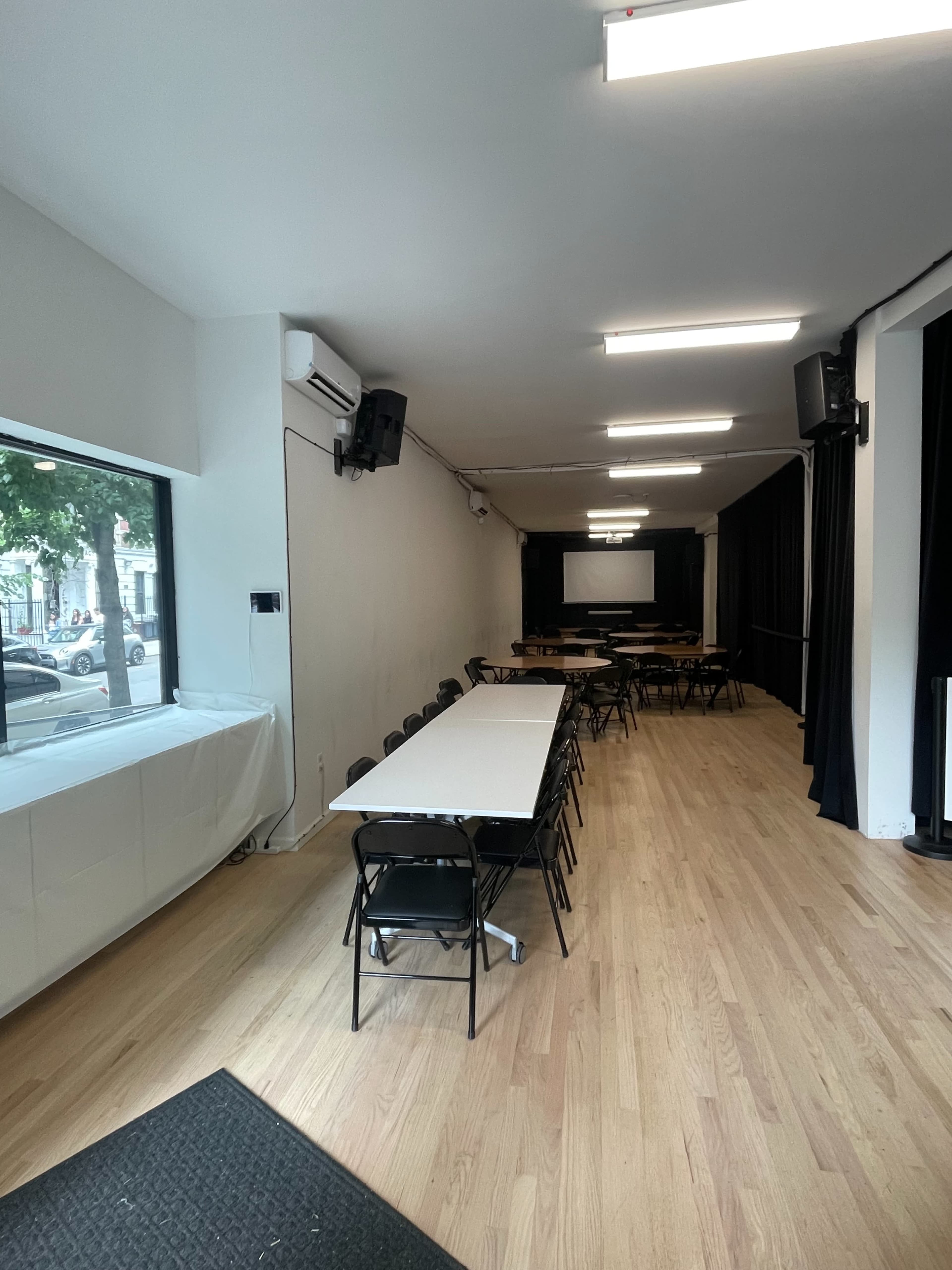 The image shows a spacious, well-lit meeting room with rows of tables and chairs set up for a gathering.