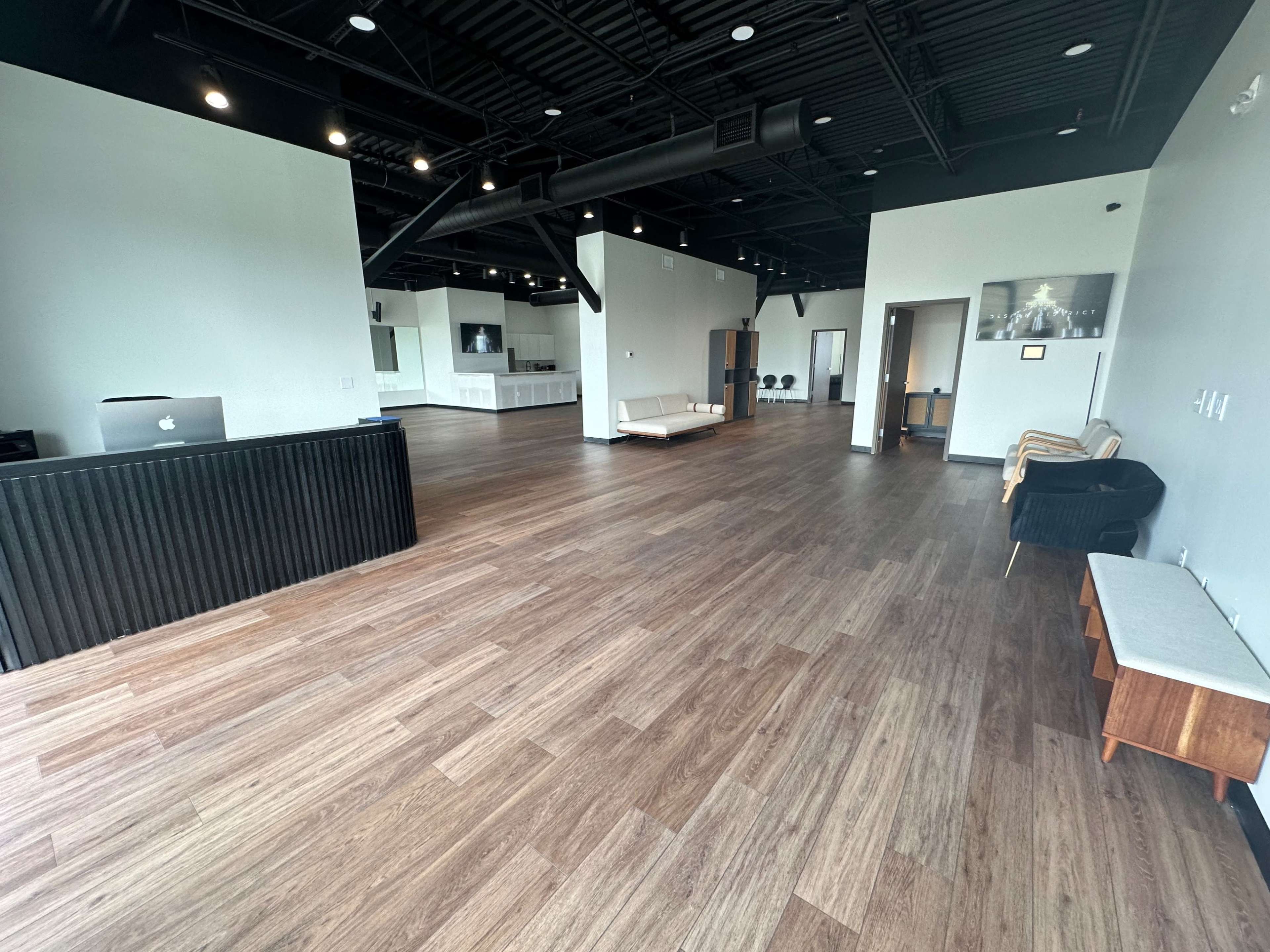 A spacious, modern interior with a wooden floor, a reception desk, and various seating areas.