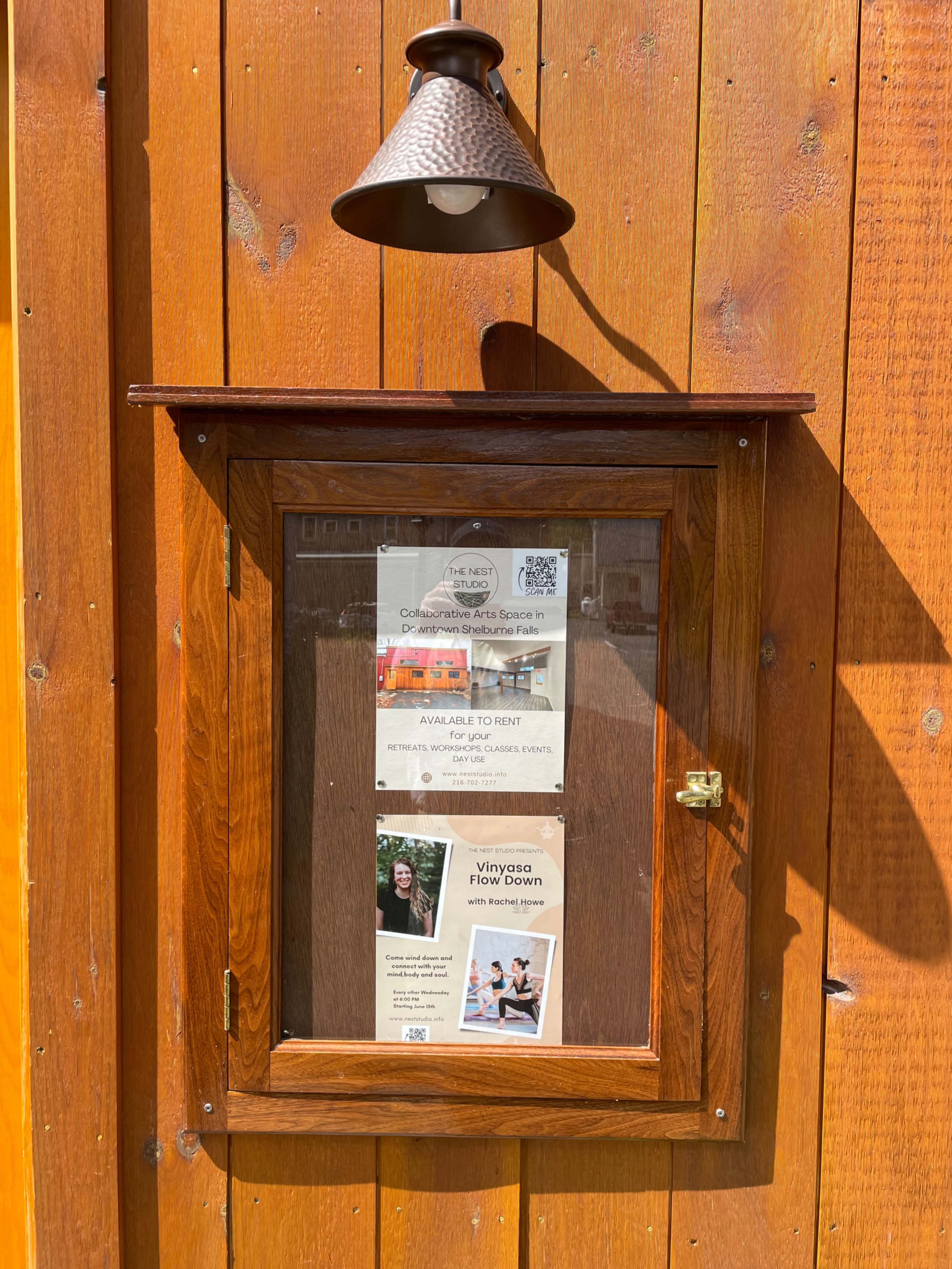 A wooden display case mounted on a wall features rental advertisements and a photo of an individual.
