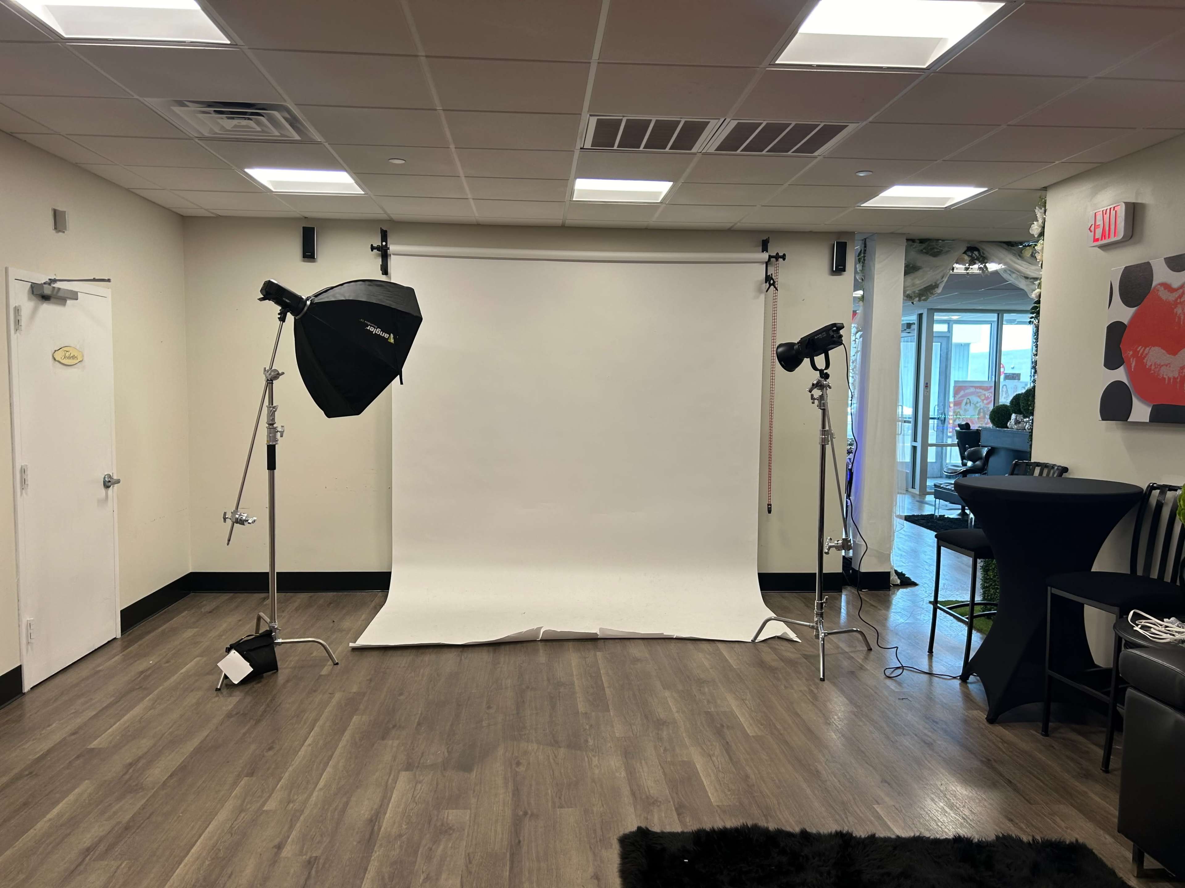 A photography studio setup featuring a white backdrop and two lights with softboxes positioned on either side.